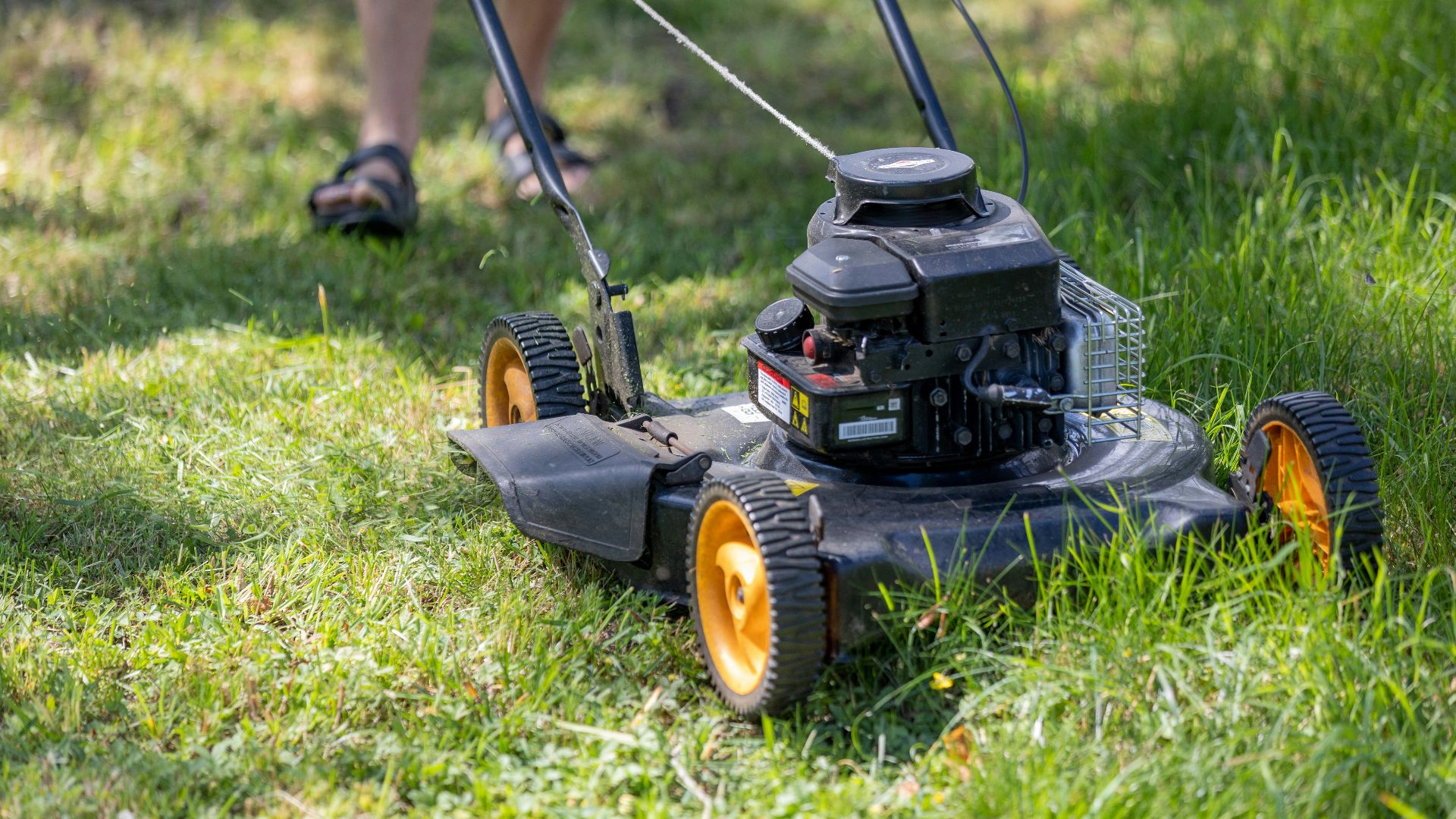 a person mowing the grass with a lawn mower