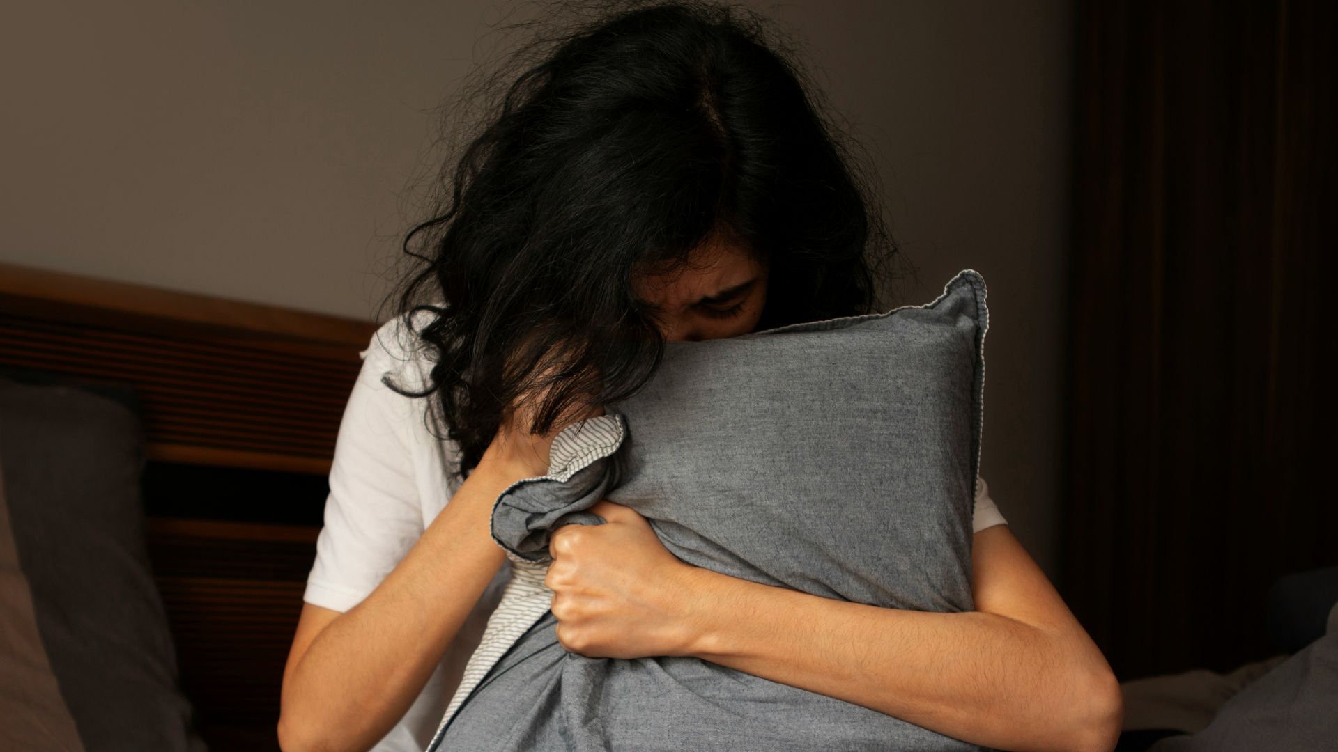 A woman sitting on a bed holding a pillow