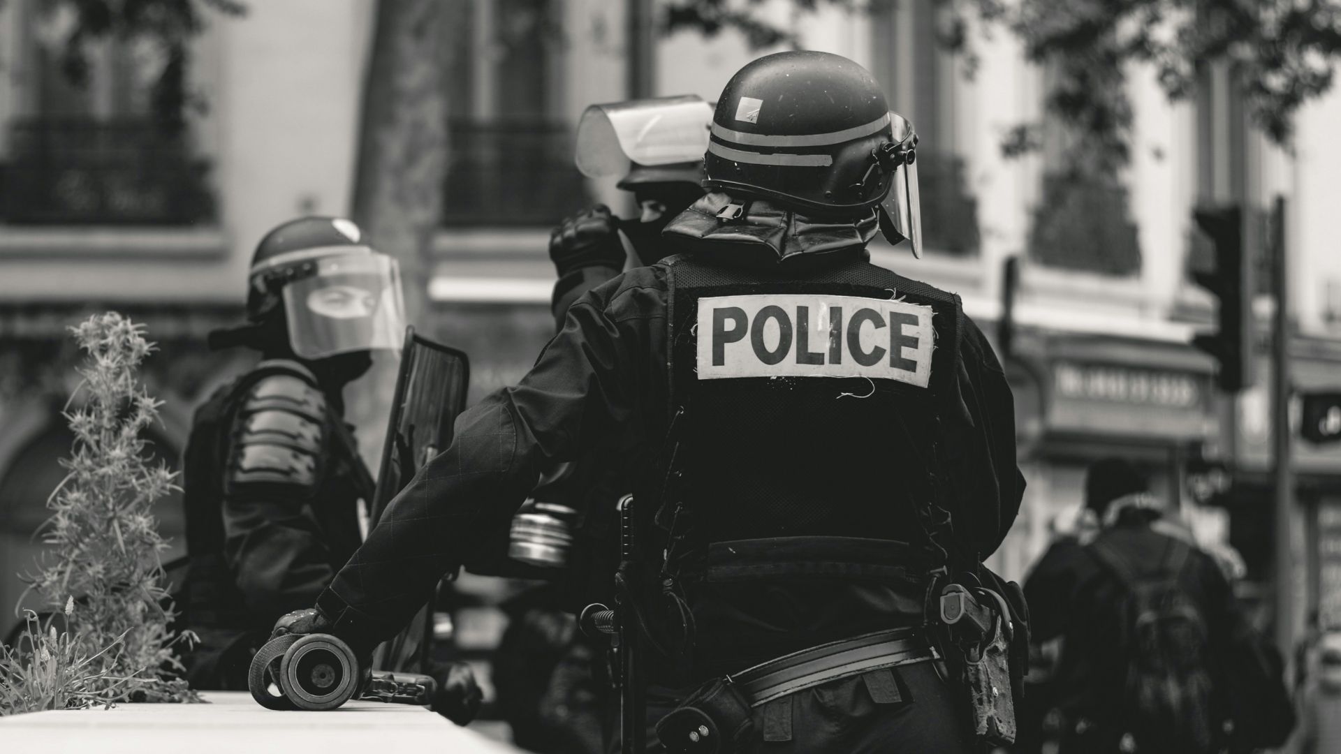 grayscale photo of Police standing and leaning on wall