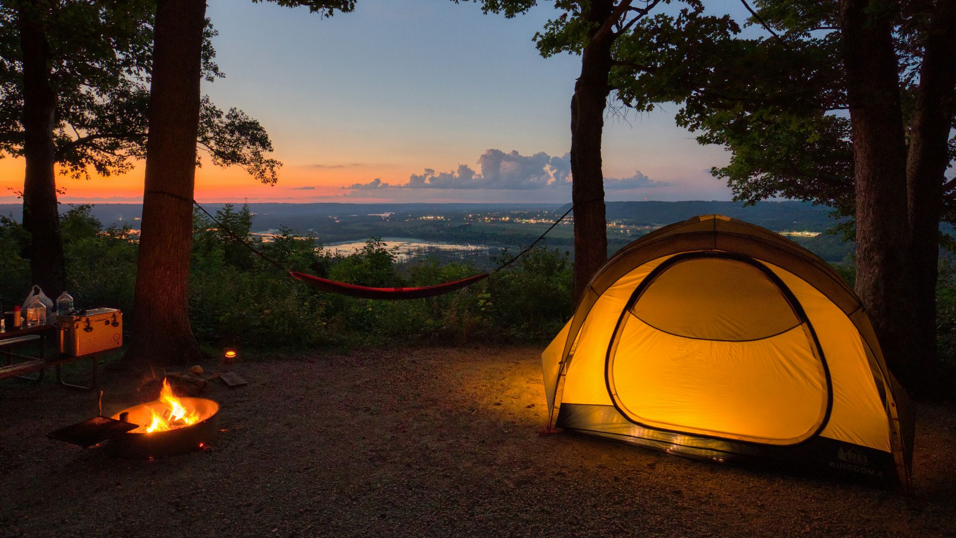 a tent set up in the woods at sunset