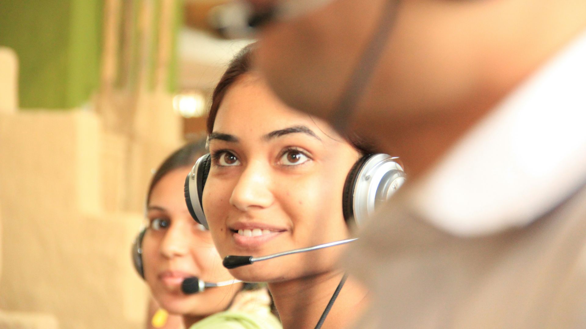 woman in black headphones holding black and silver headphones