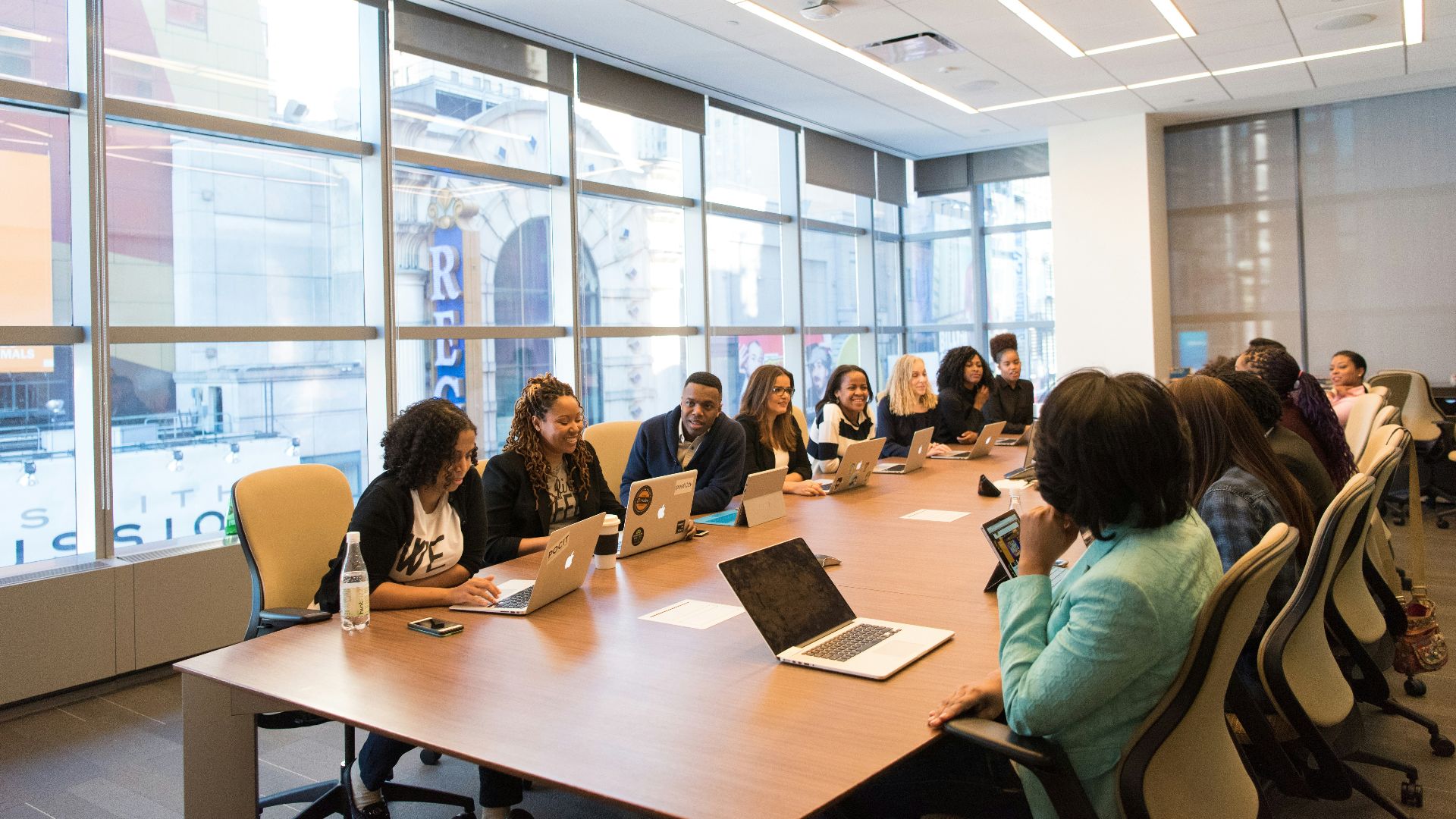 group of people sitting beside rectangular wooden table with laptops