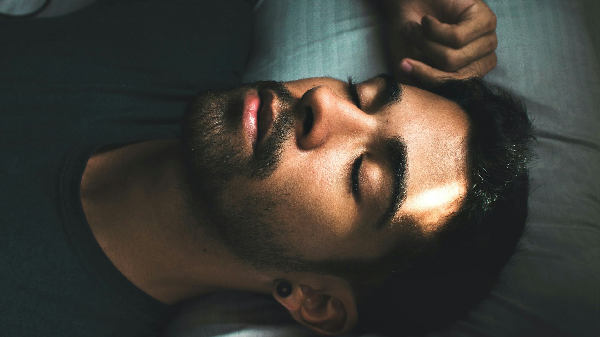man in black crew neck t-shirt lying on bed