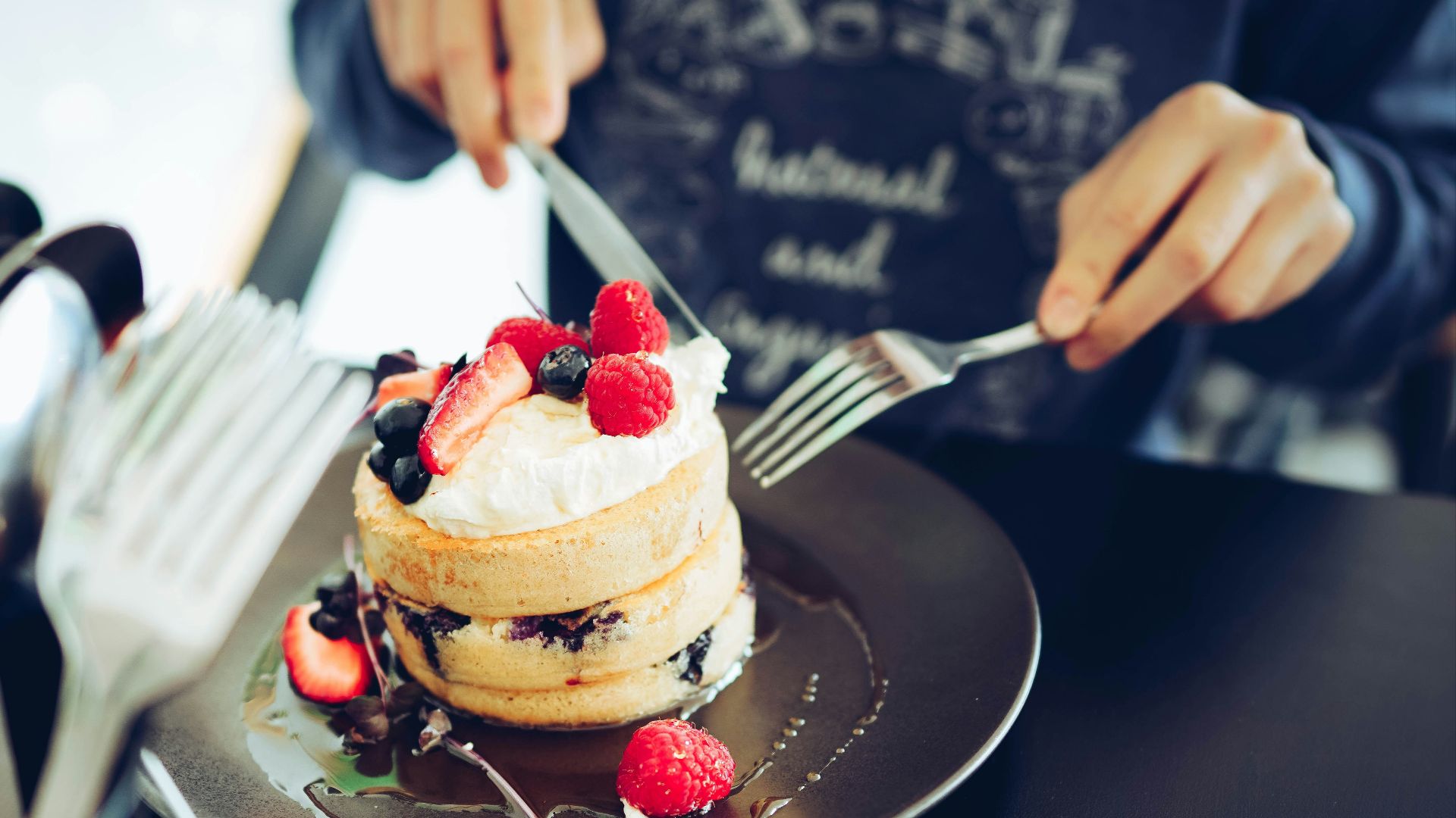 a person cutting a cake with a knife and fork
