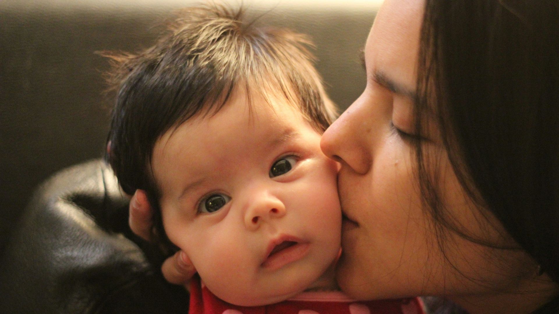 a woman kissing a baby on the cheek