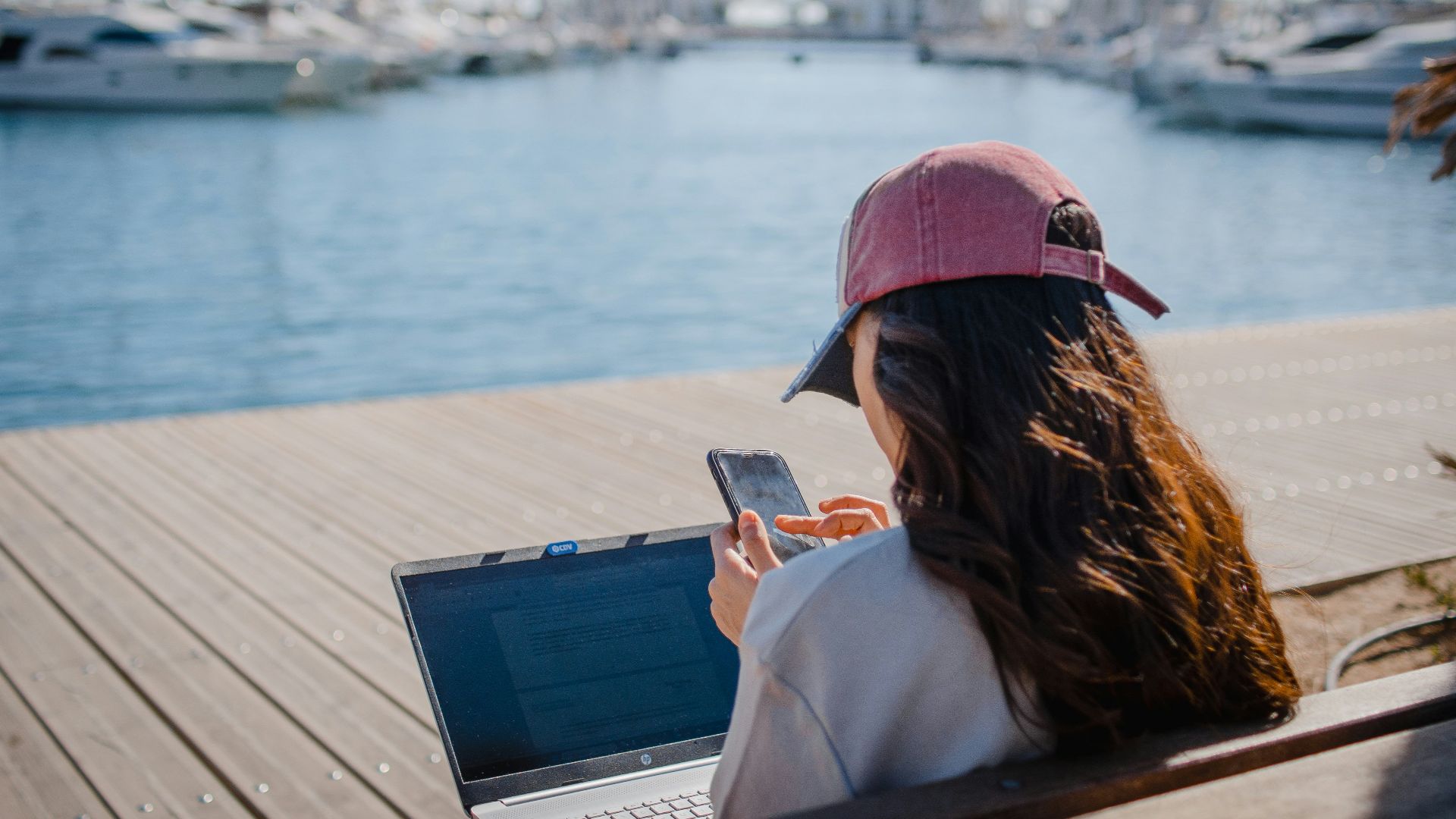a woman sitting on a bench using a laptop computer
