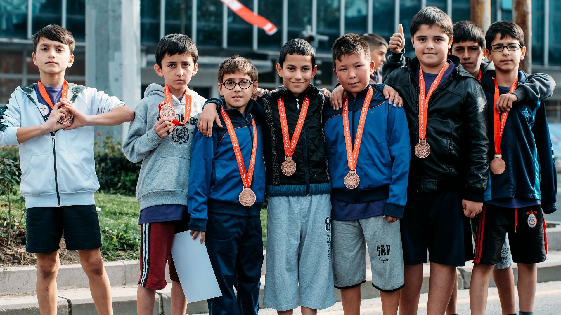 group of children wearing medal standing near wall