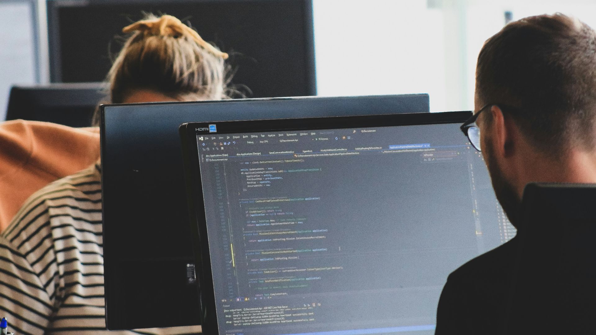 woman in black shirt sitting beside black flat screen computer monitor