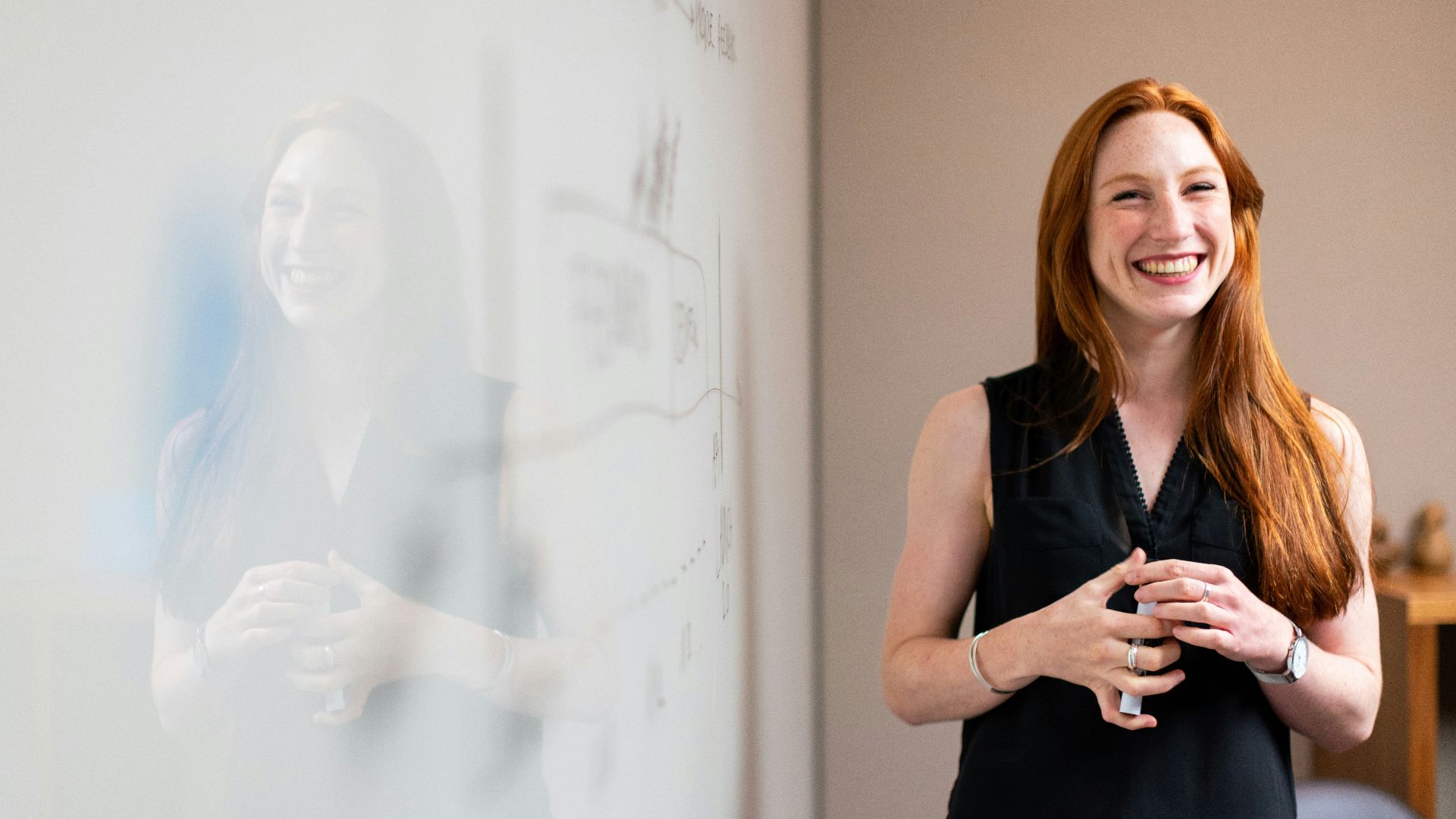 woman in blue tank top standing beside white wall