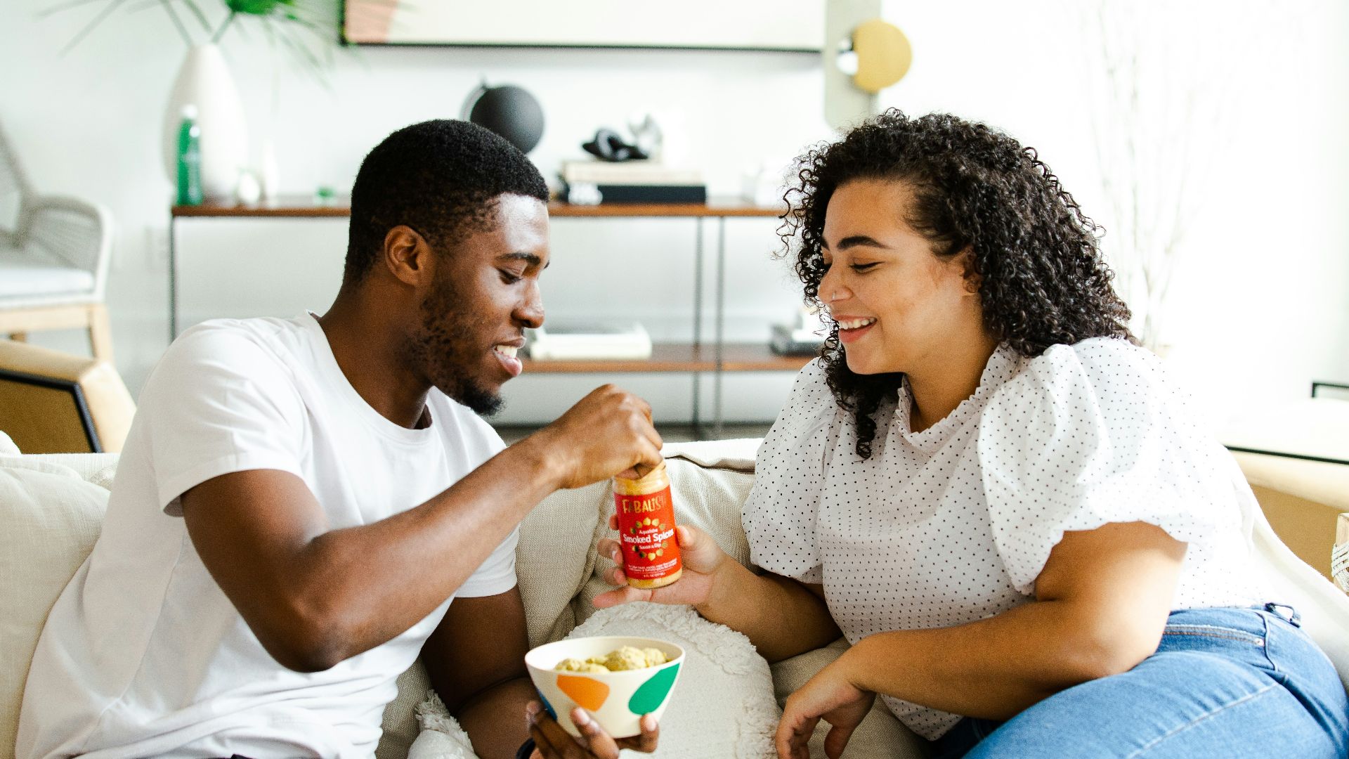 man in white crew neck t-shirt and blue denim jeans sitting on white sofa chair