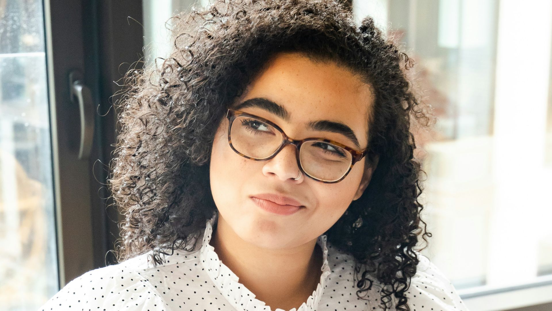 woman in white and black polka dot shirt holding blue and white book