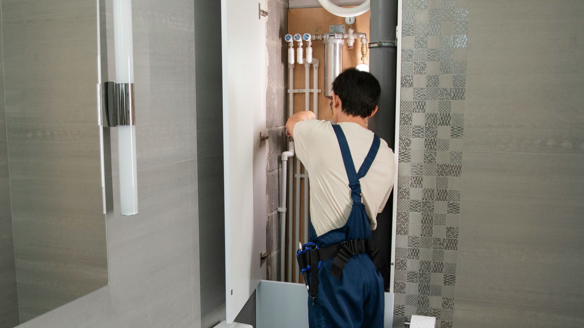 A plumber repairs plumbing in a bathroom.