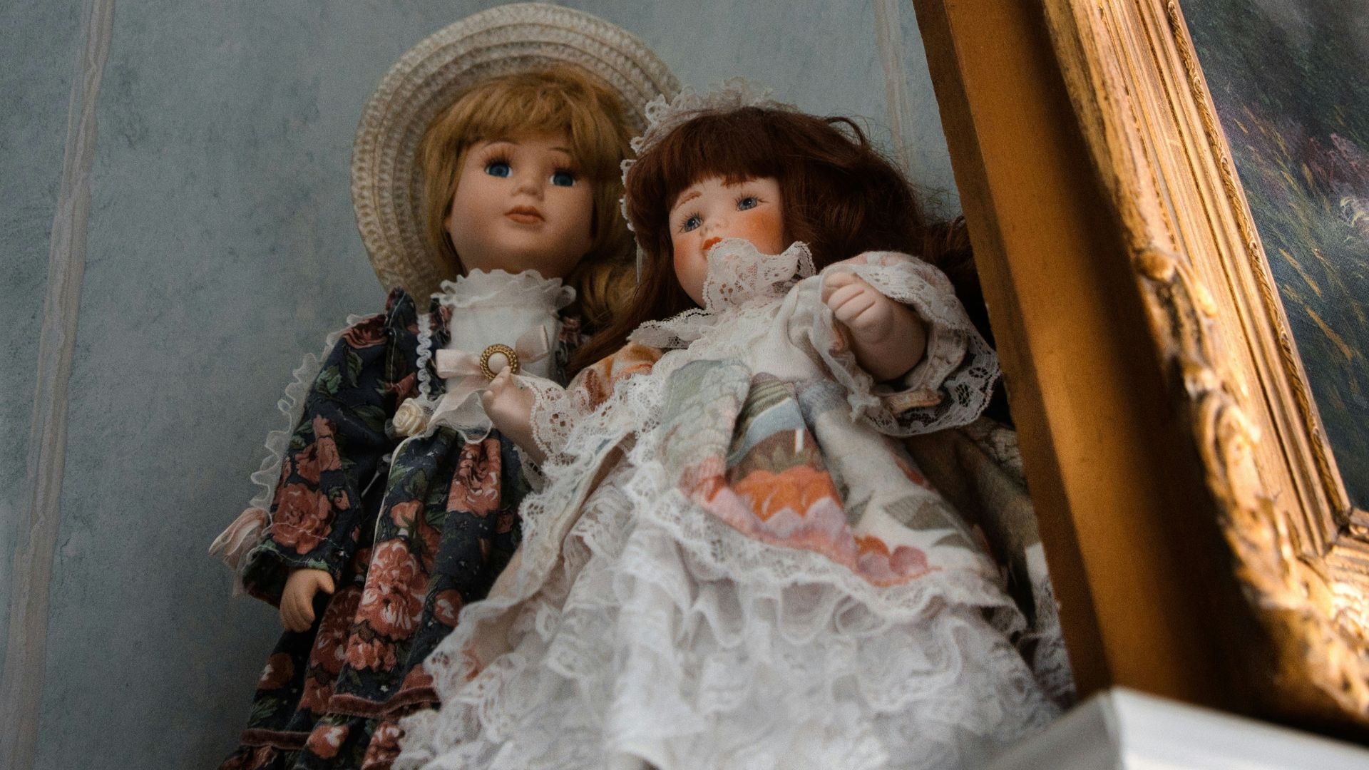 Two antique dolls in ornate dresses and vintage dresses.
