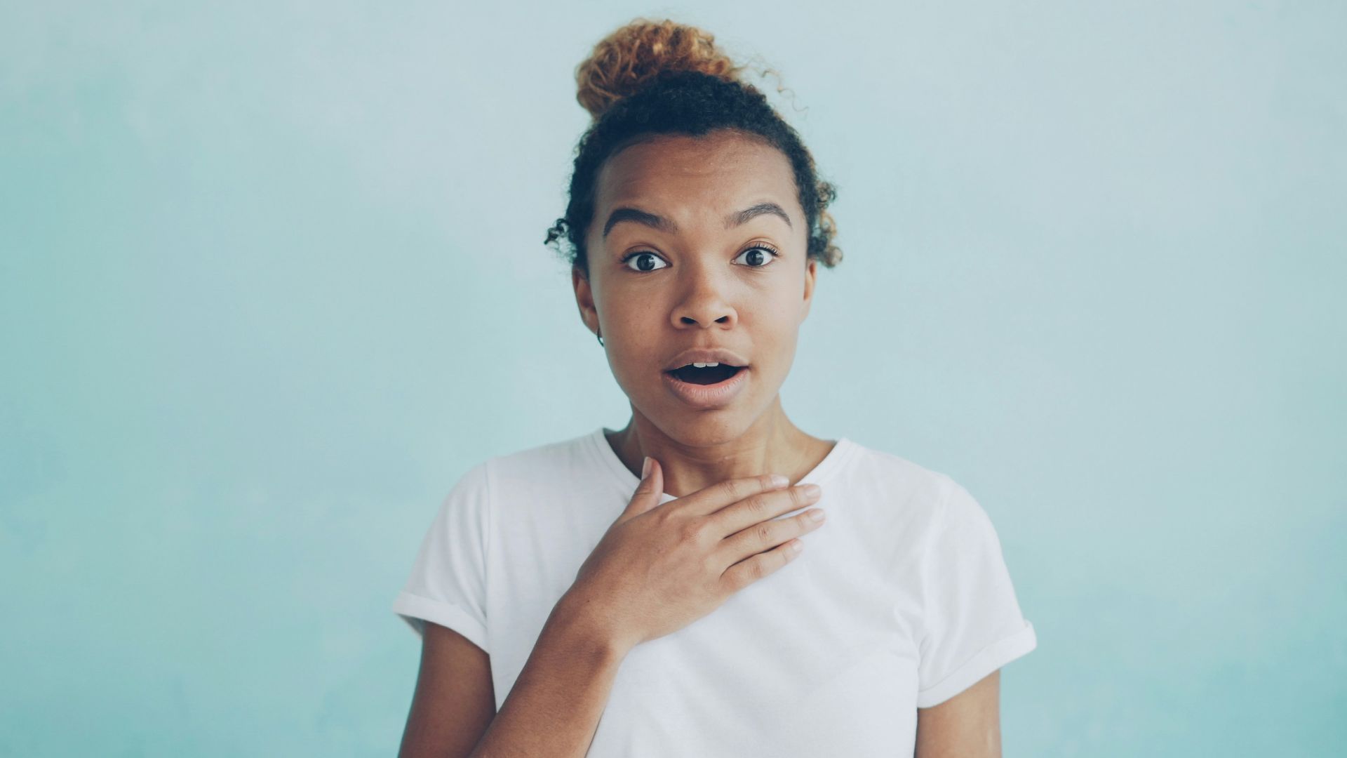Young woman with hand on chest, surprised expression.