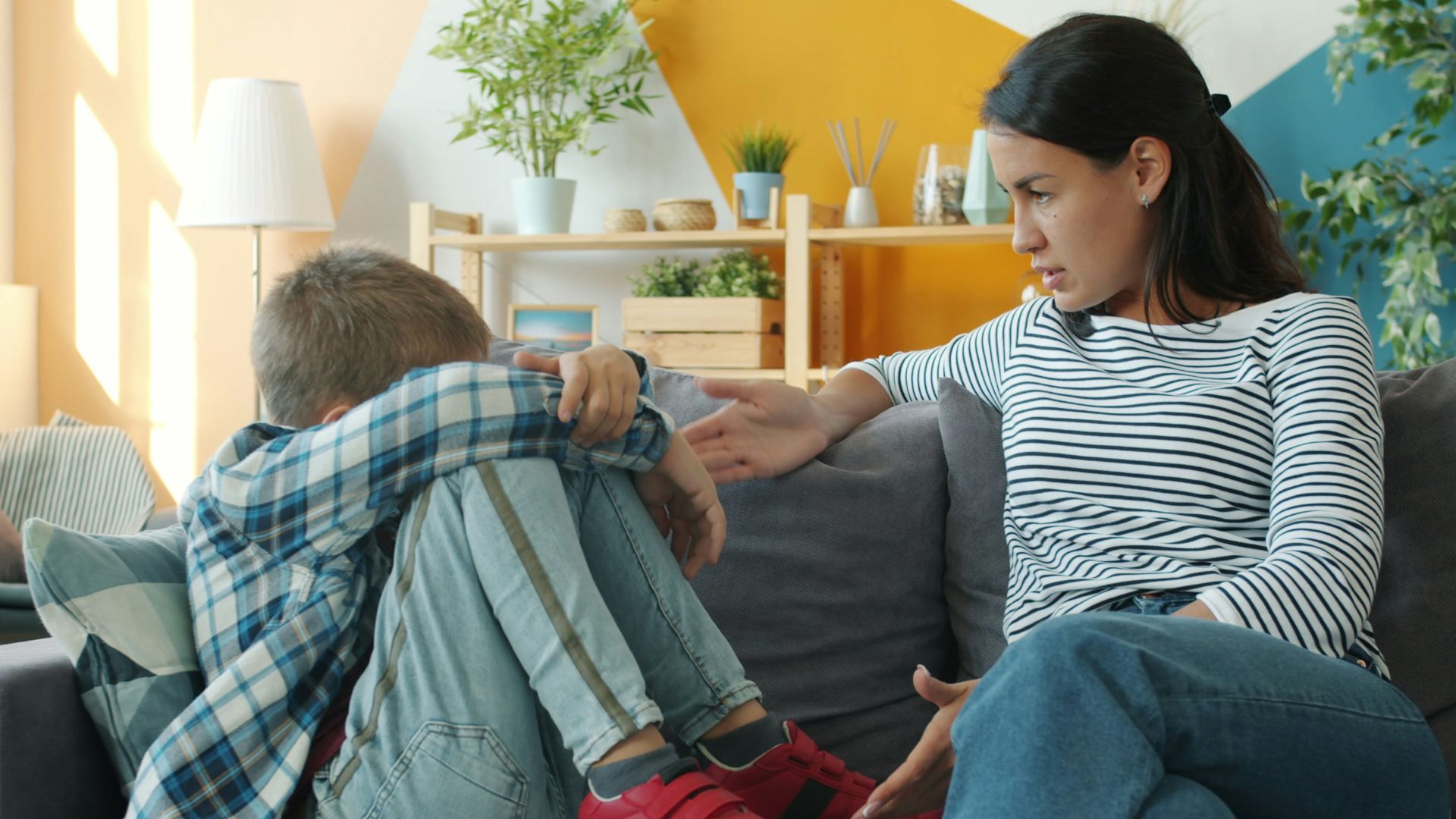 Mother comforts upset child on the sofa