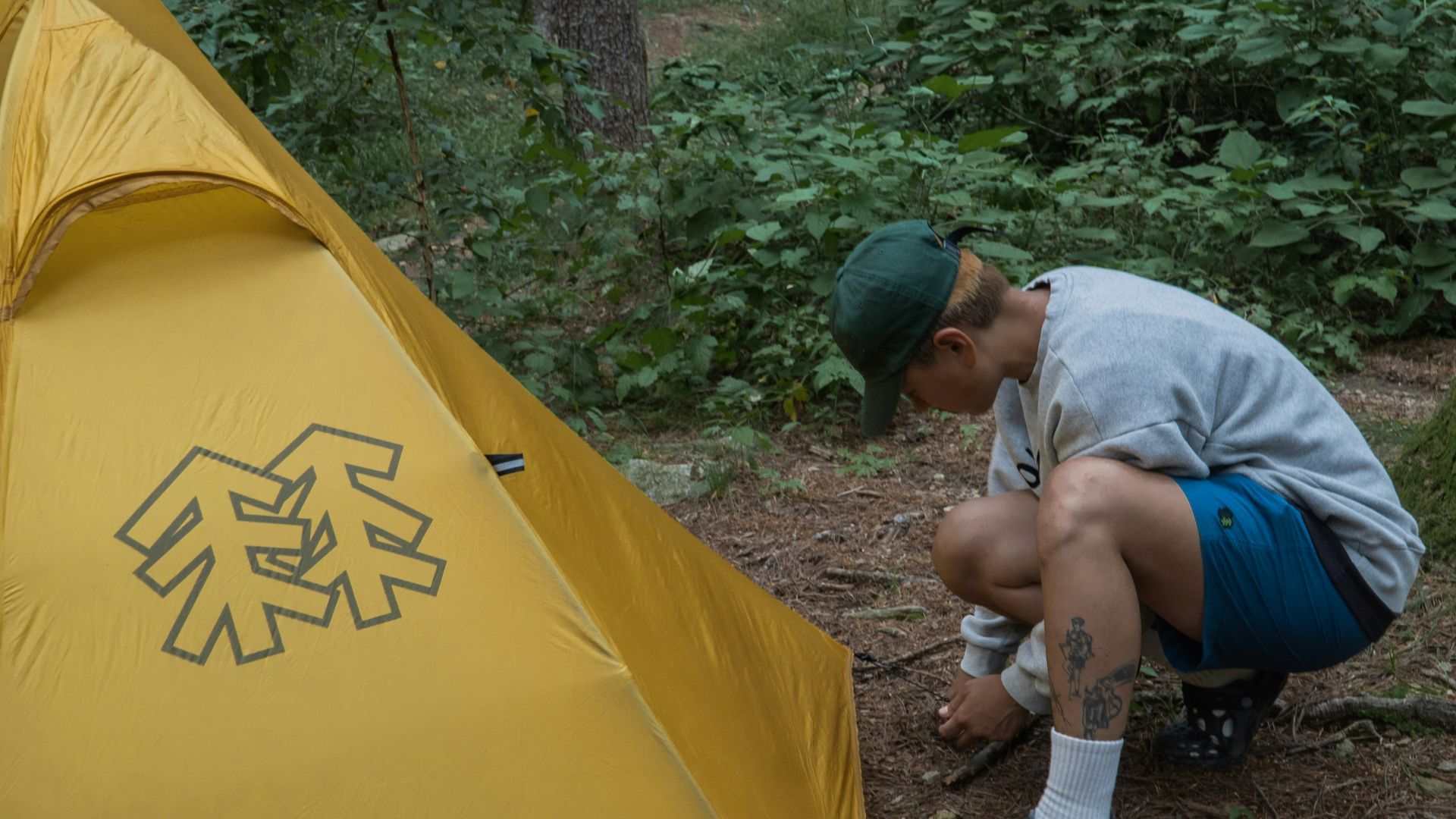 a man kneeling down next to a yellow tent