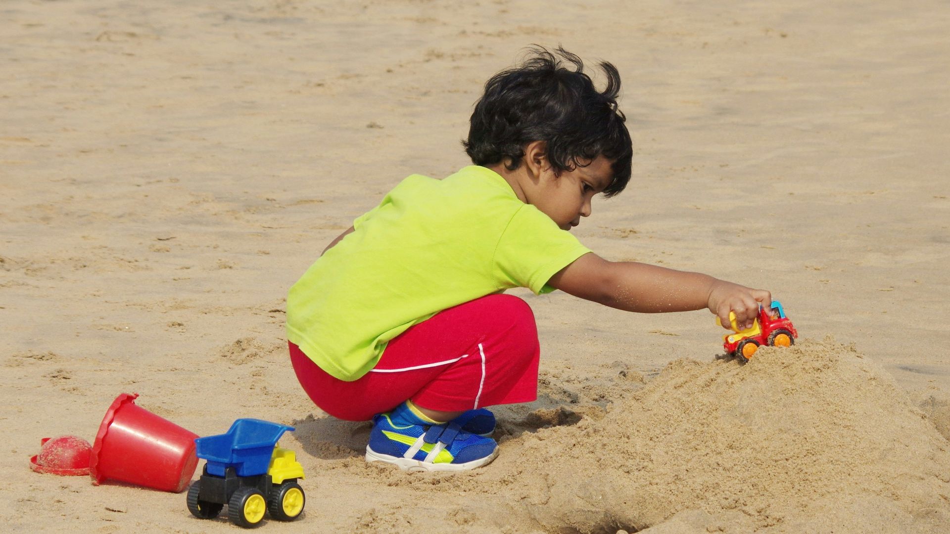 a little boy playing in the sand with a toy truck