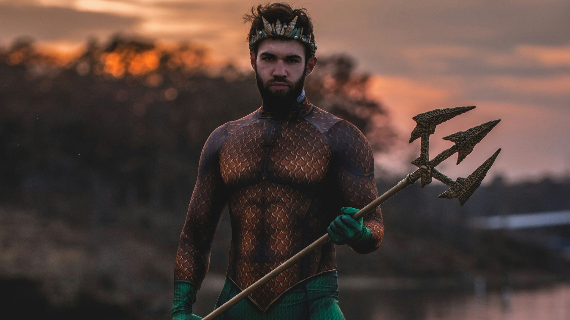 man wearing Poseidon costume standing on rock