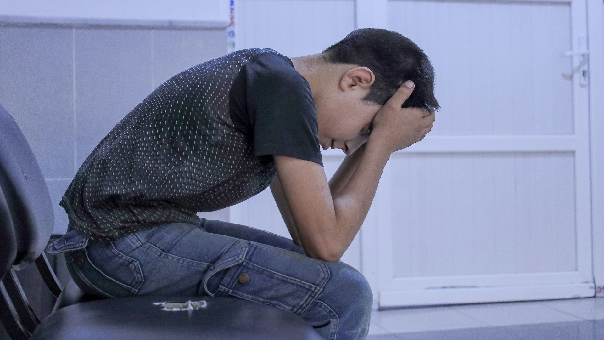 A man sitting on a chair with his head in his hands