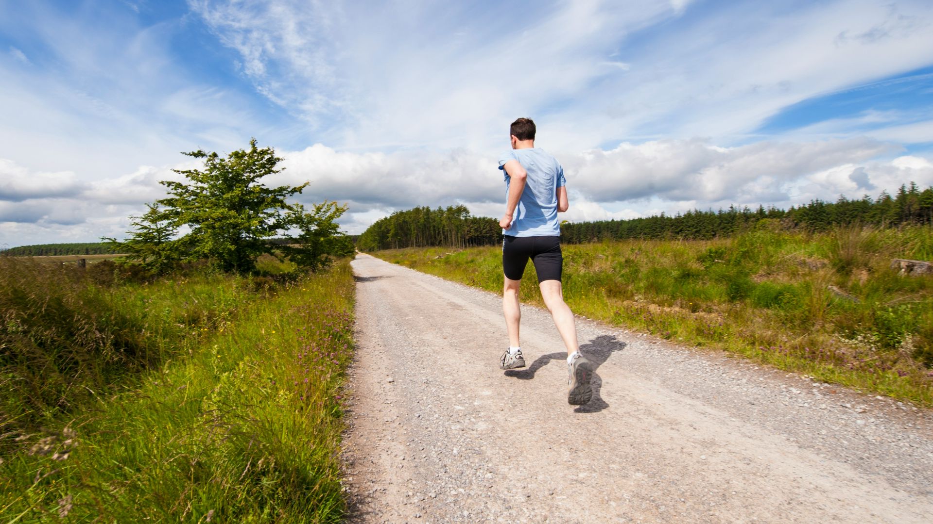 man running on road near grass field