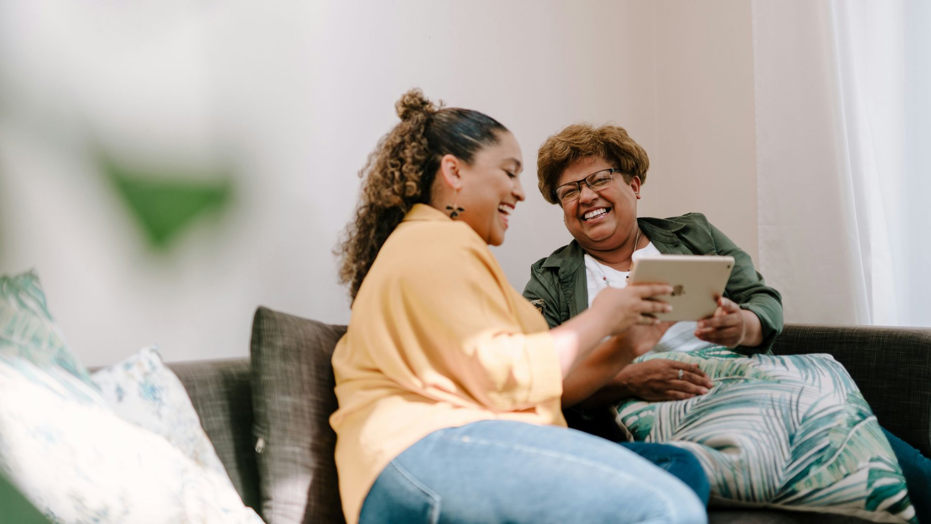 a man and woman sitting on a couch looking at a tablet