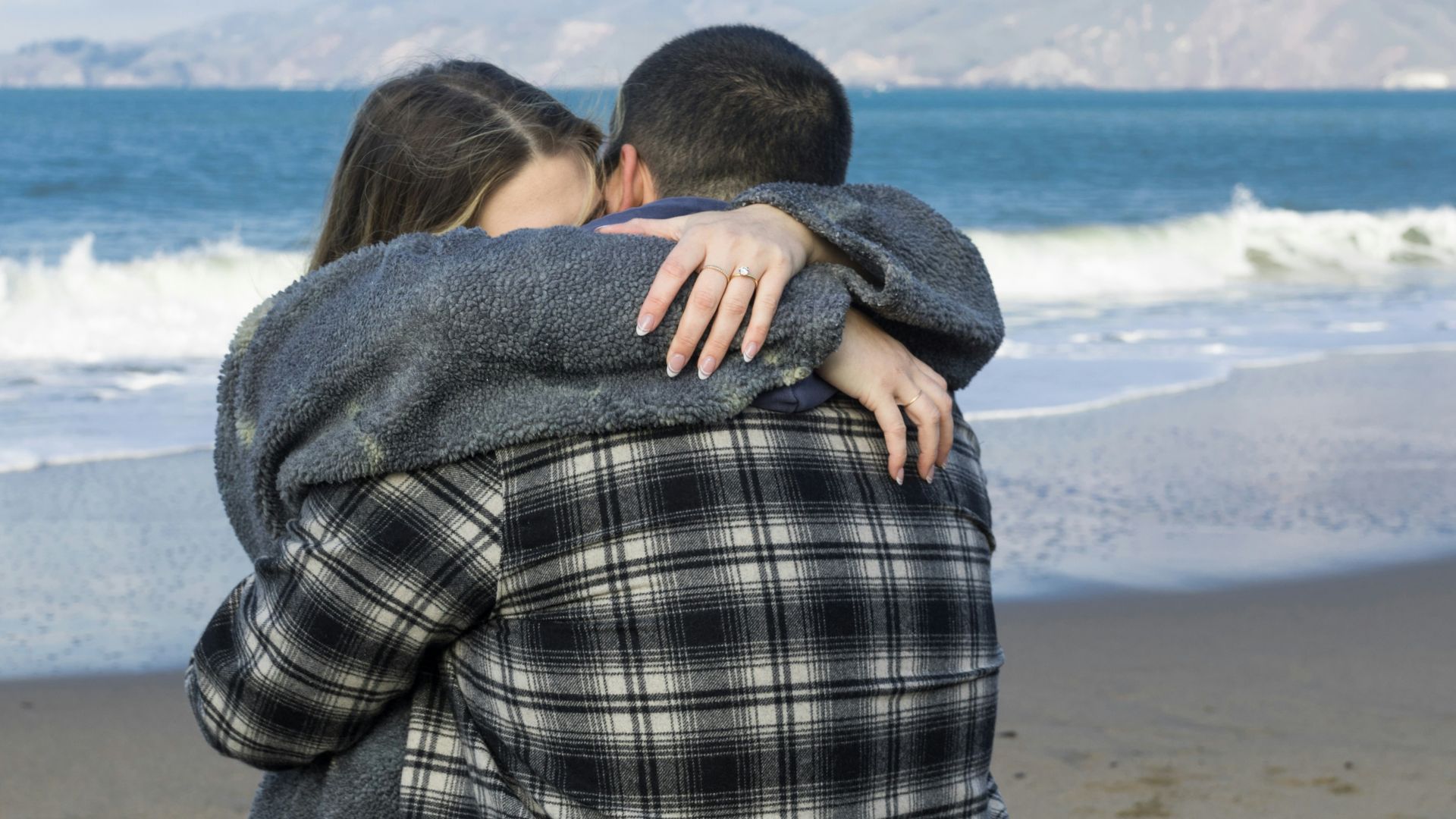 a man and a woman hugging on the beach
