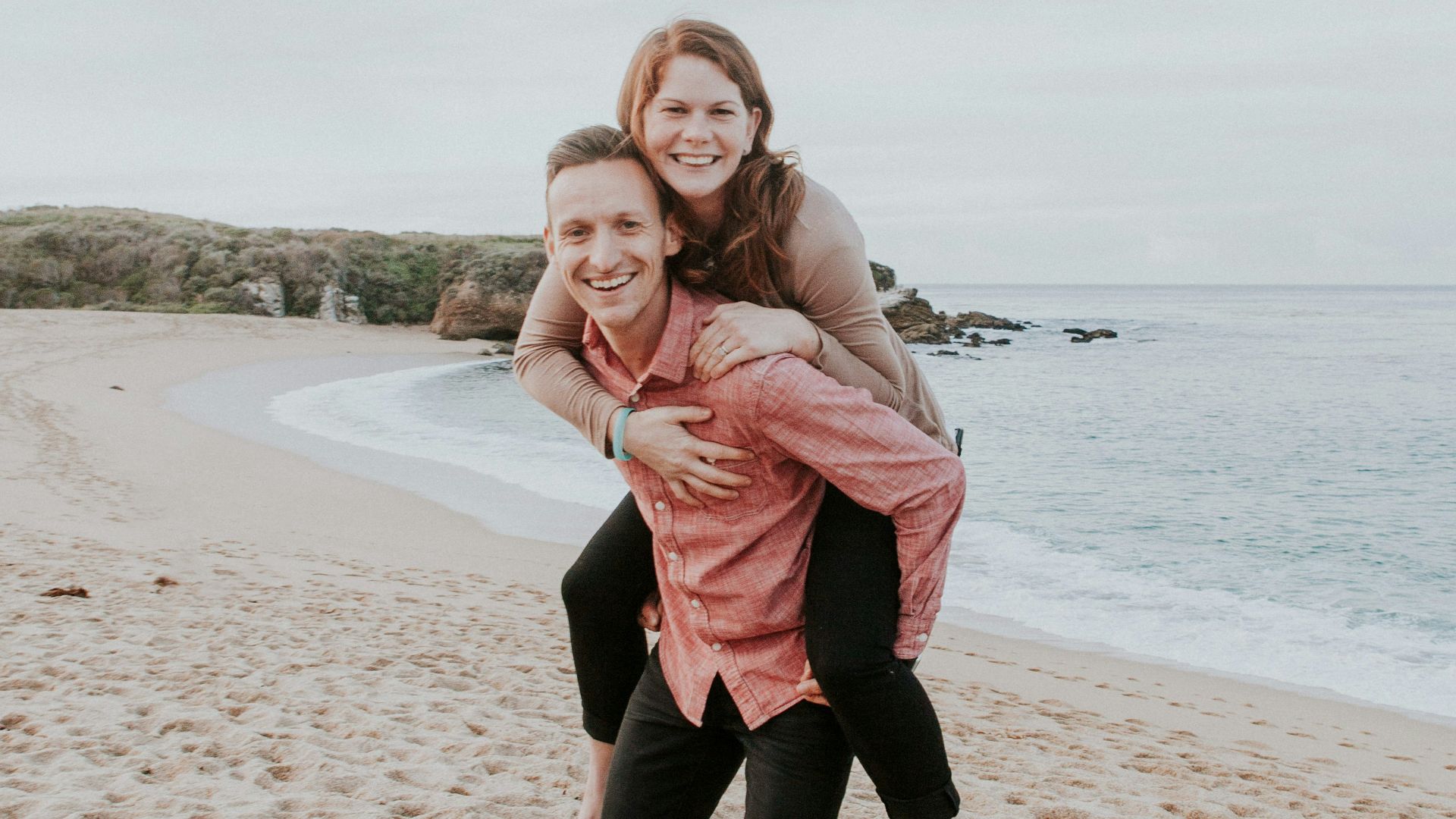 man carrying woman beside seashore