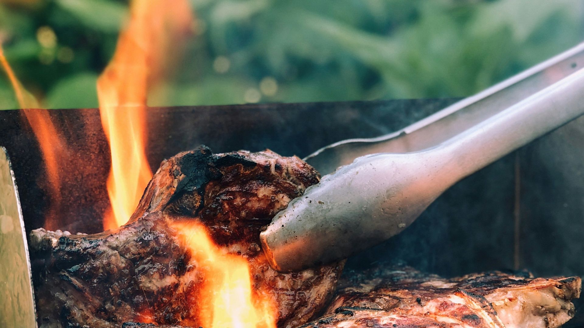gray metal tong and grilled meat with fire