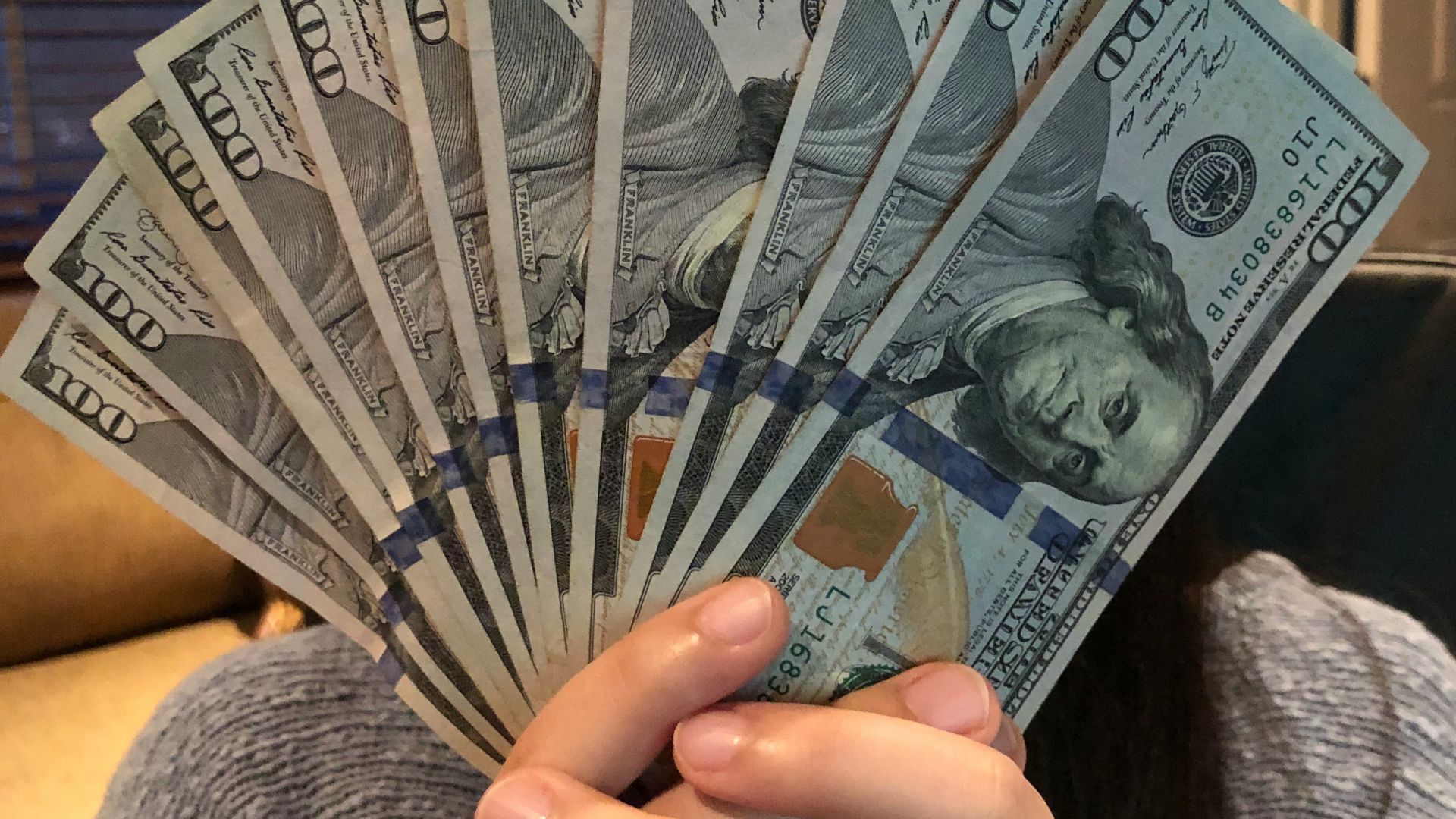 person holding fan of us dollar bill
