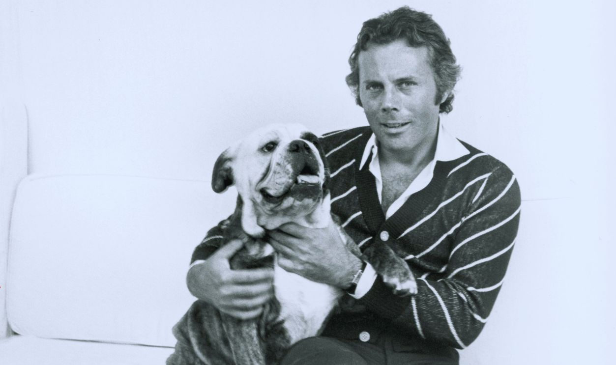 Gettyimages - 1460915121, Giorgio Armani: The blazer's edge, Milan Italian fashion designer Giorgio Armani sitting on a couch with his legs crossed and hugging a pet bulldog 