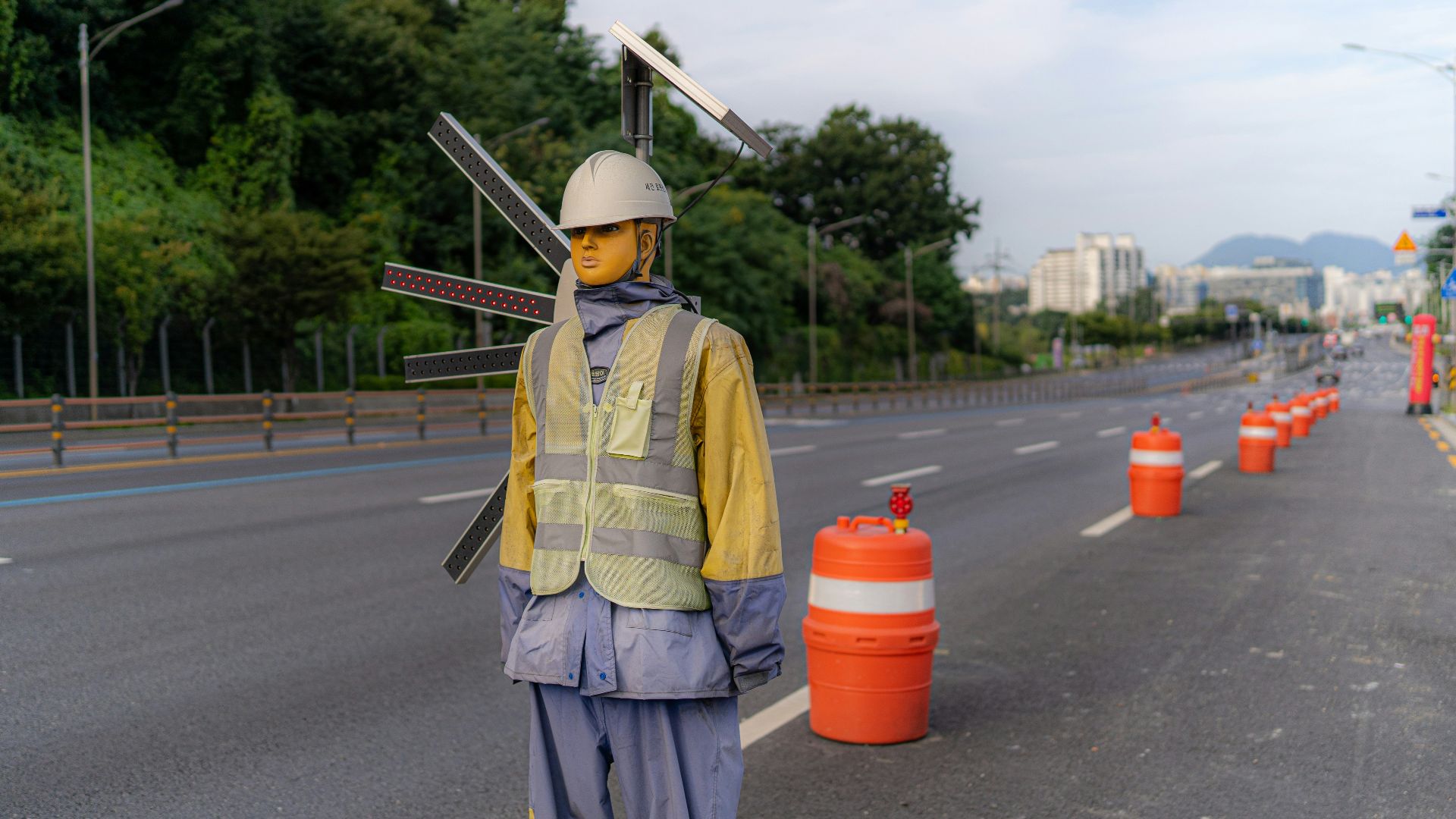 man in yellow vest and gray pants standing on road during daytime
