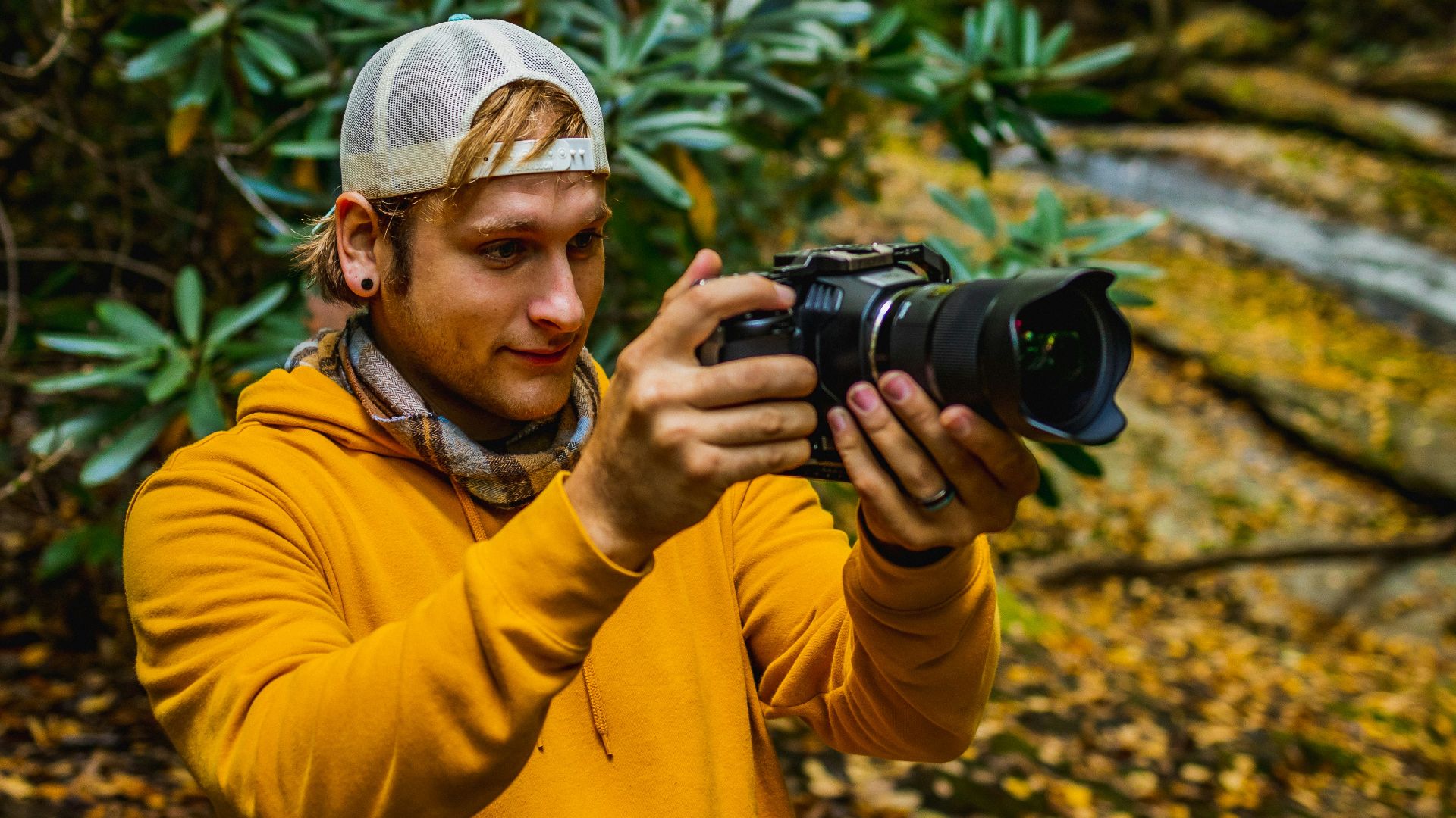 man in yellow jacket holding black dslr camera