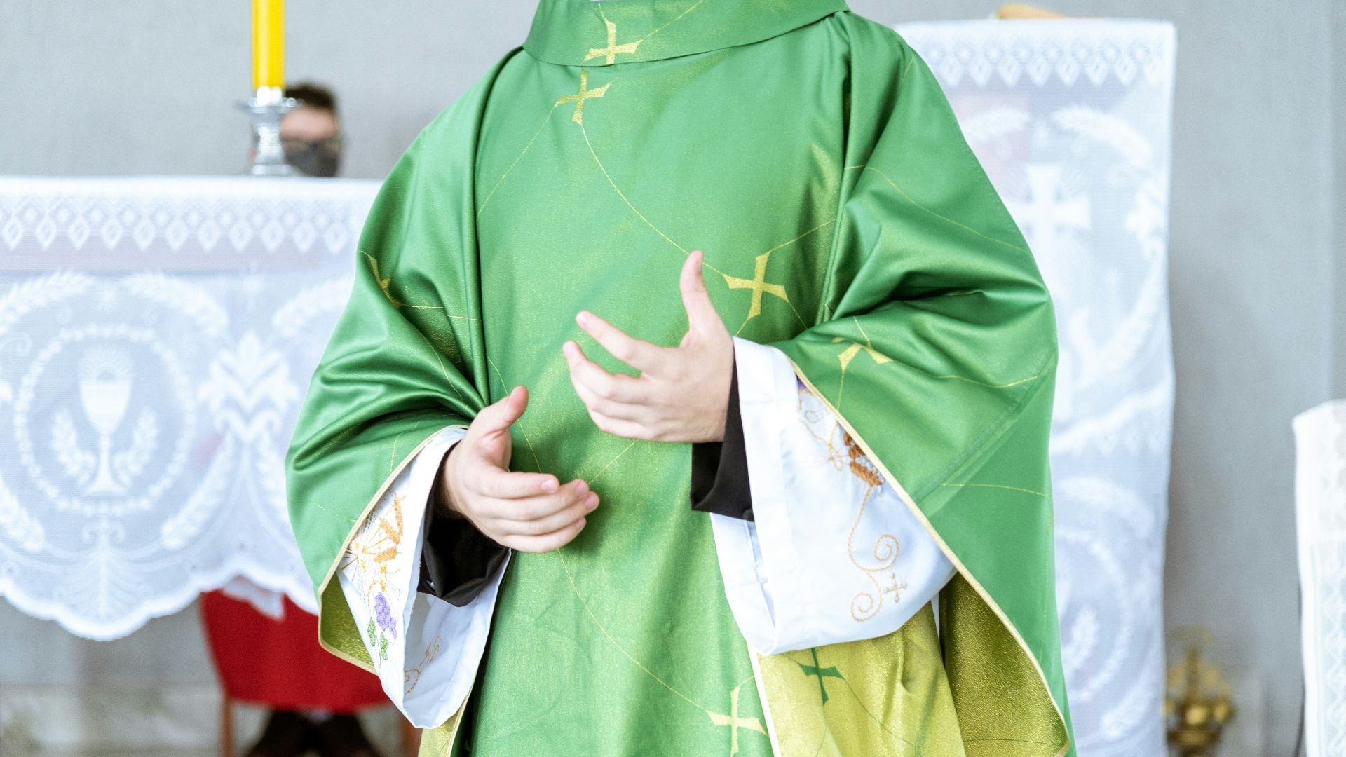 a man in a priest's outfit standing in front of a cross