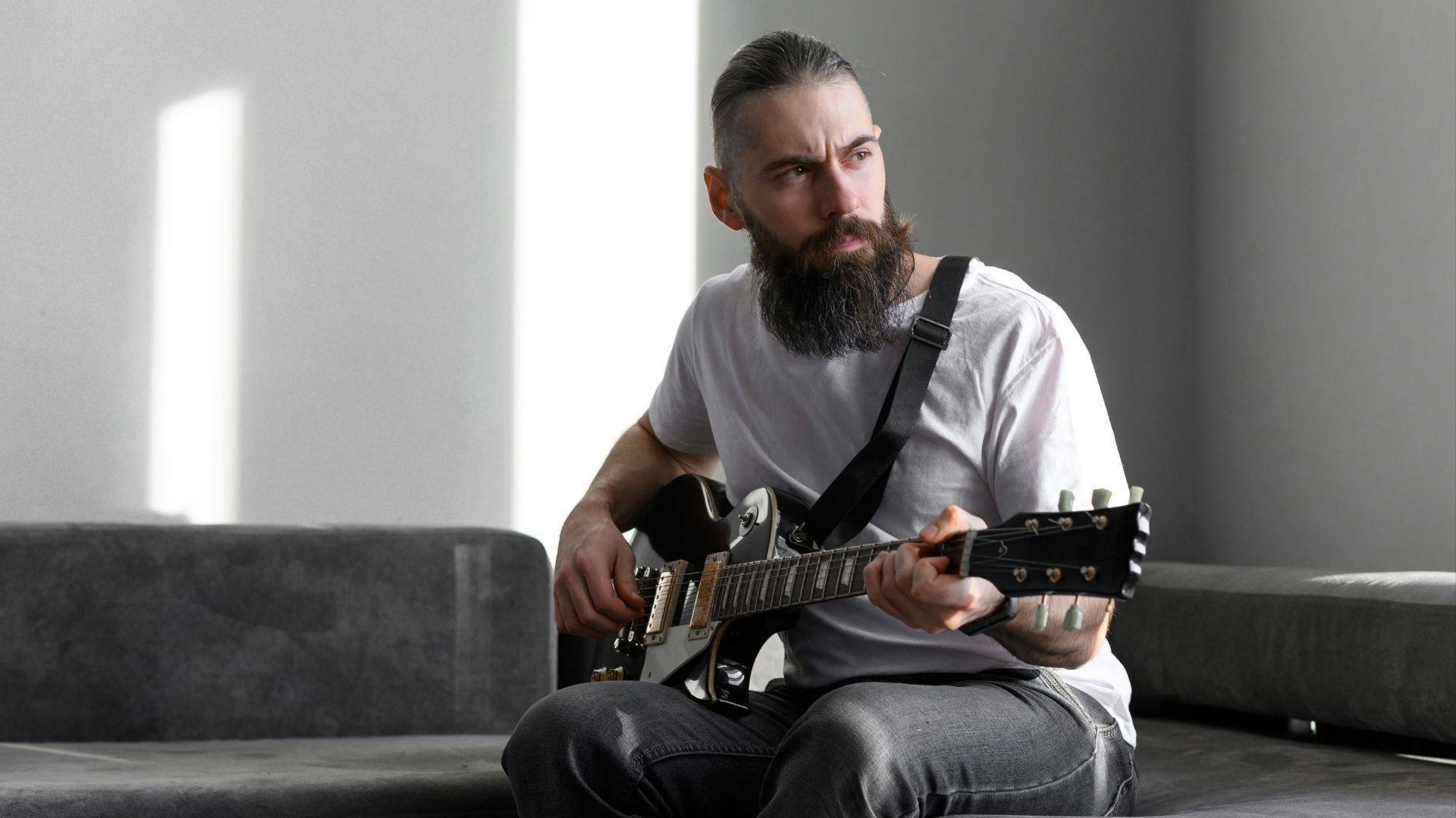 a man sitting on a couch playing a guitar