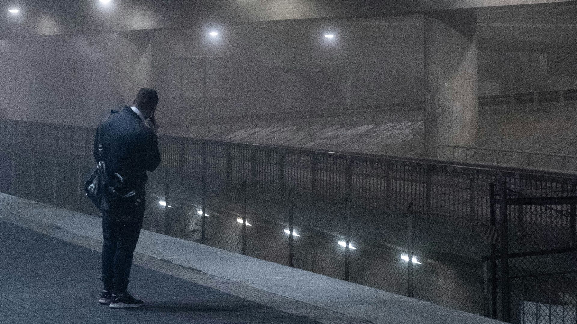 man in black jacket walking on sidewalk during night time