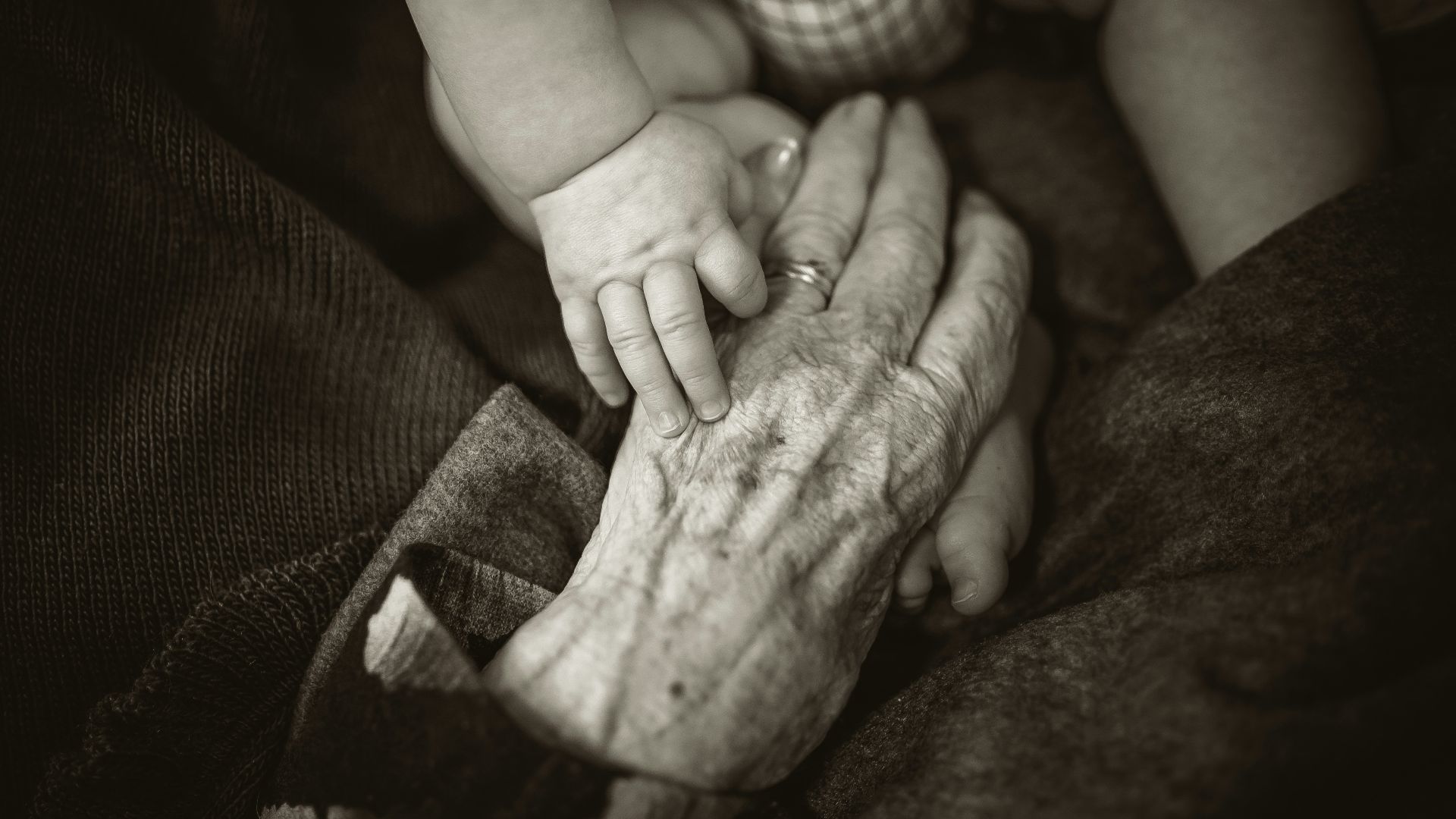 an older woman holding a baby's hand