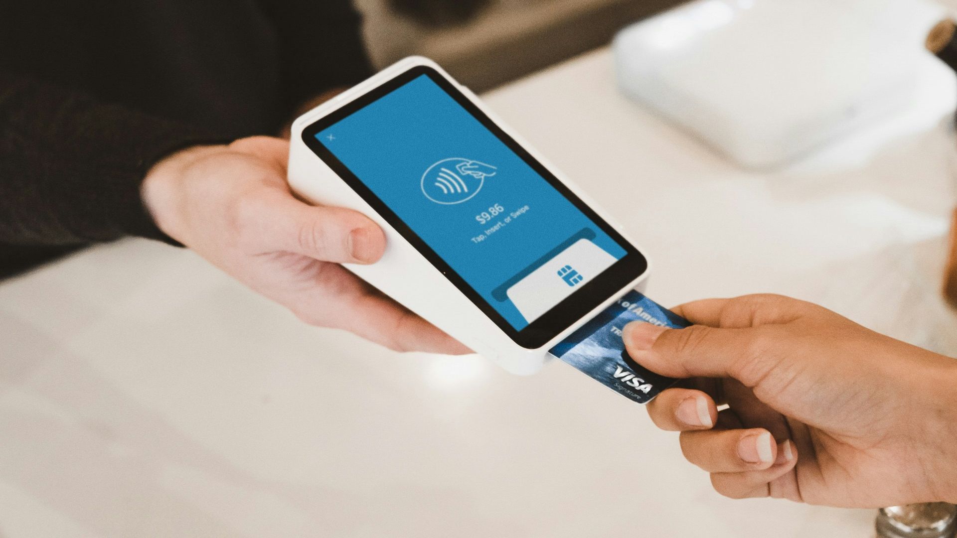 person putting magstripe card near black card terminal