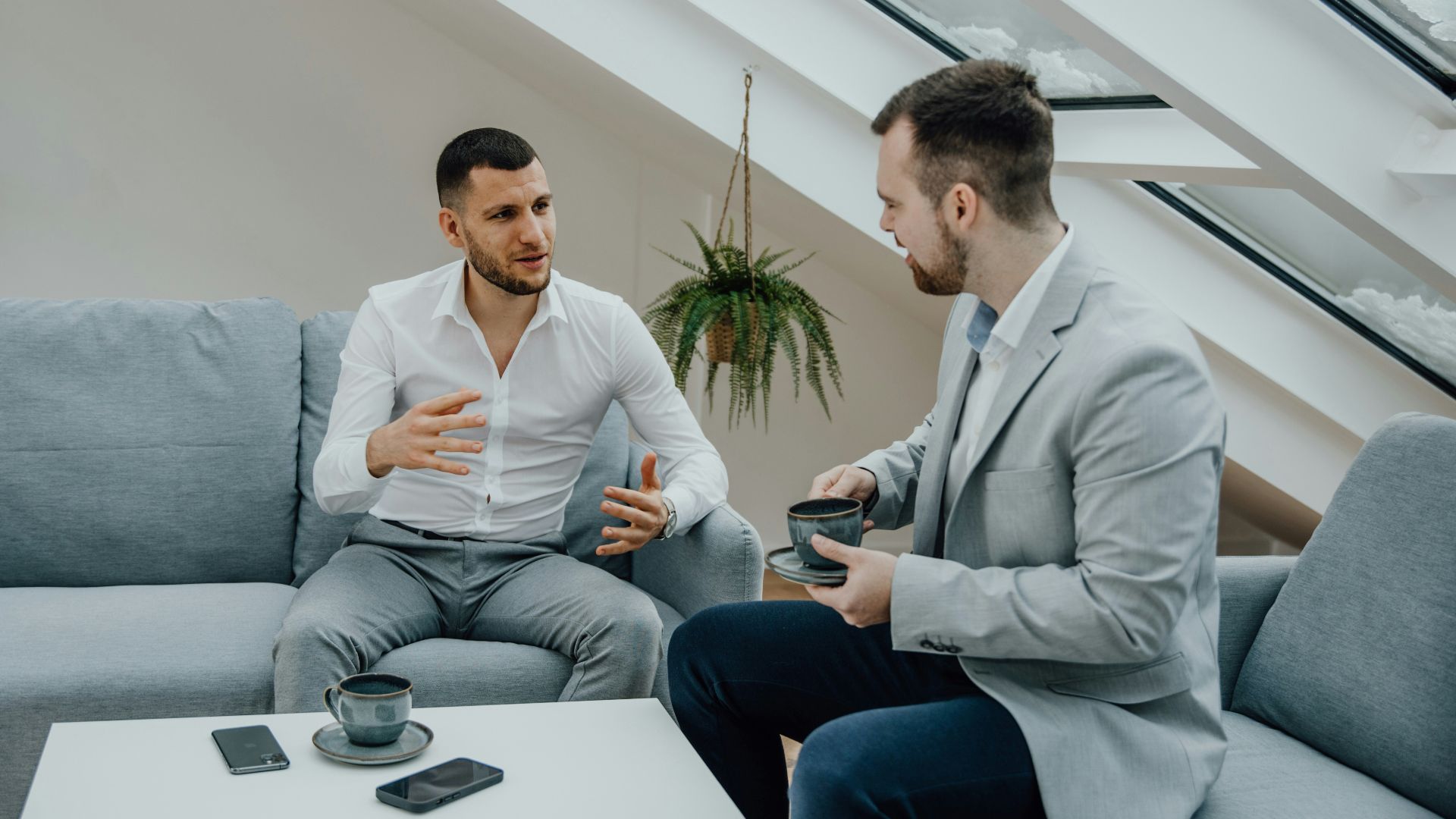 two men sitting on a couch talking to each other