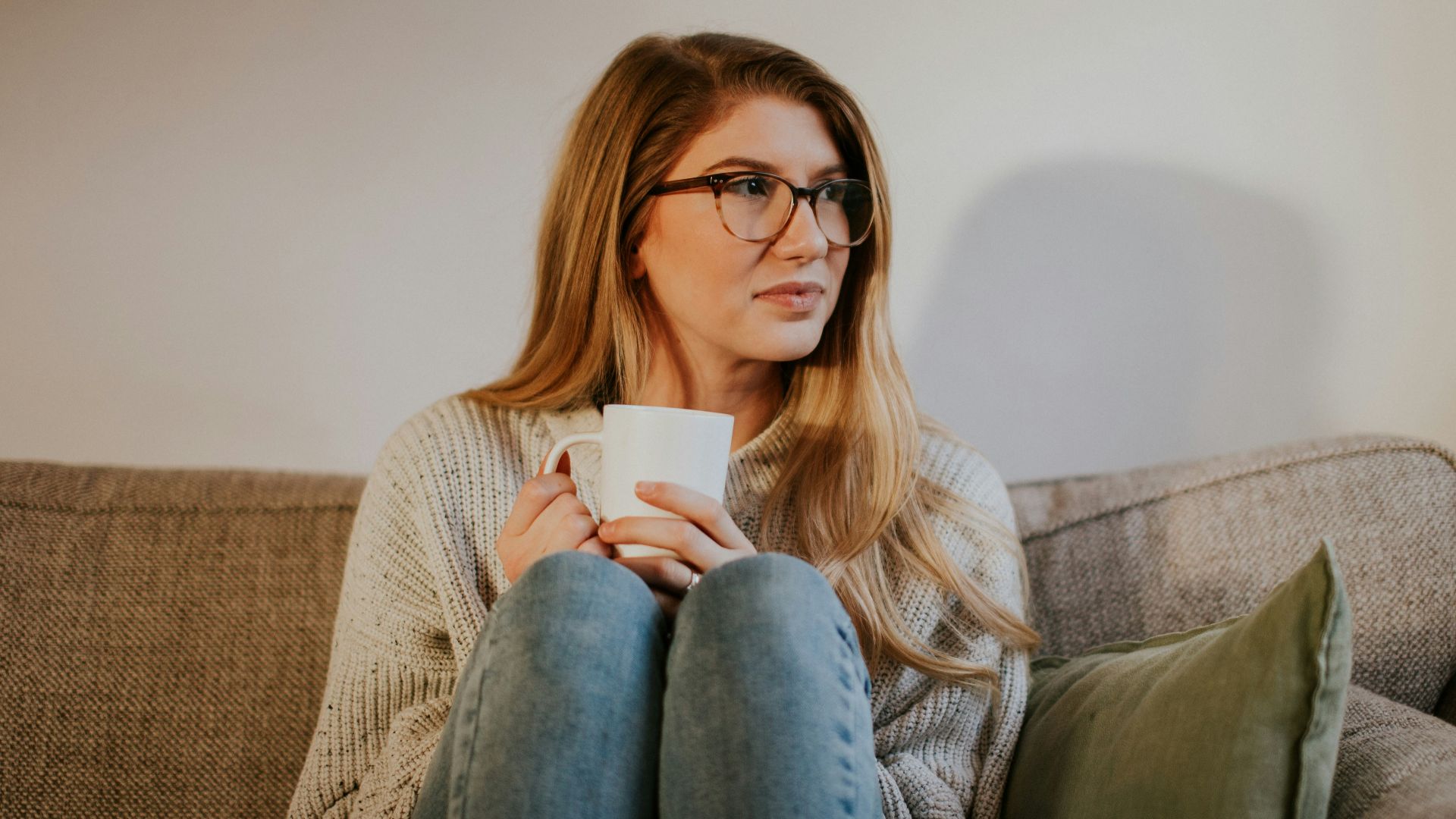 woman in blue denim jeans sitting on gray sofa