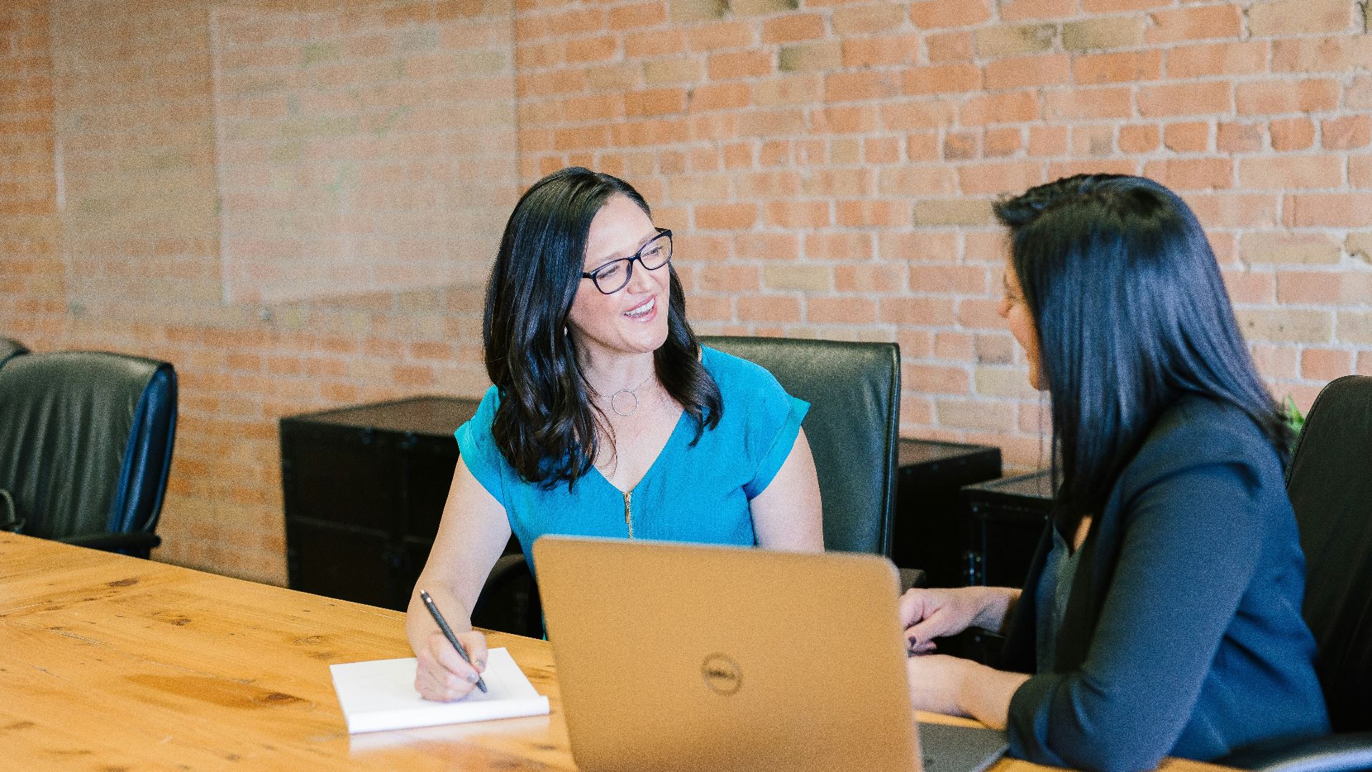 woman in teal t-shirt sitting beside woman in suit jacket
