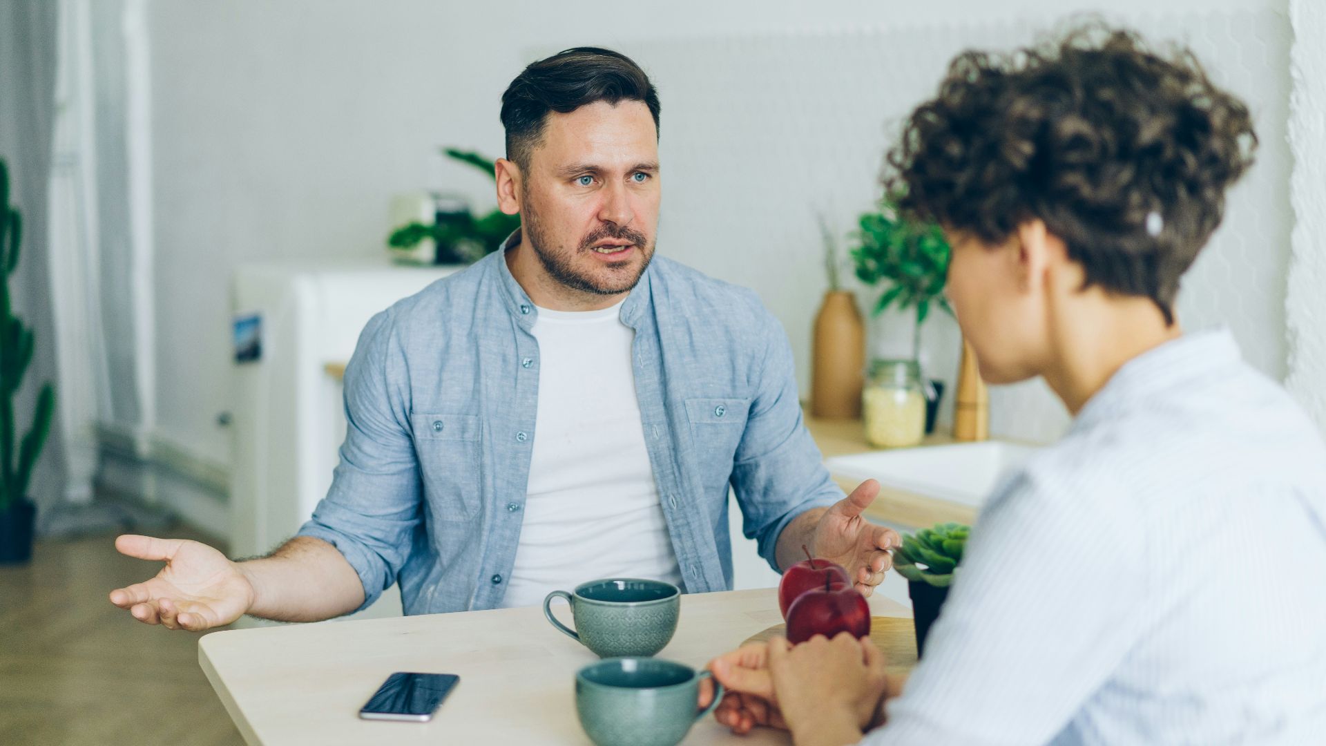 a man sitting at a table talking to a woman