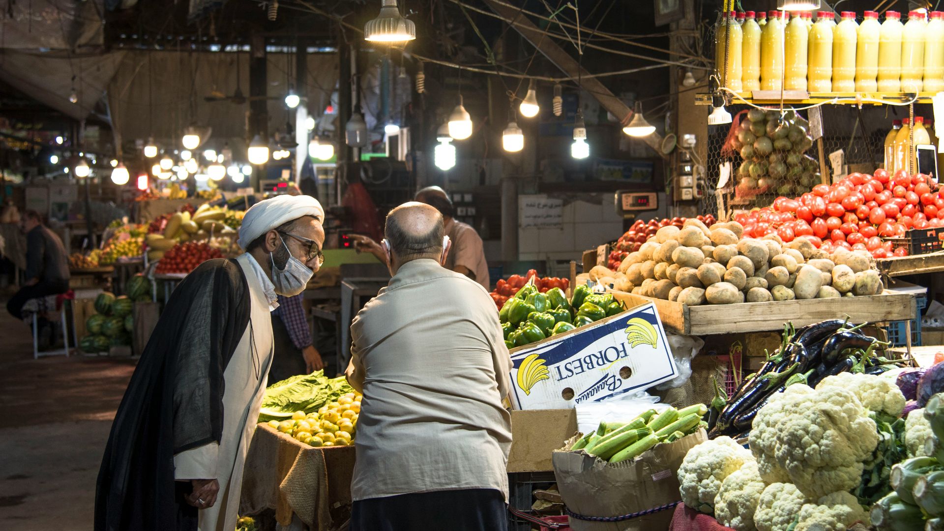 man in gray shirt standing in front of fruit stand