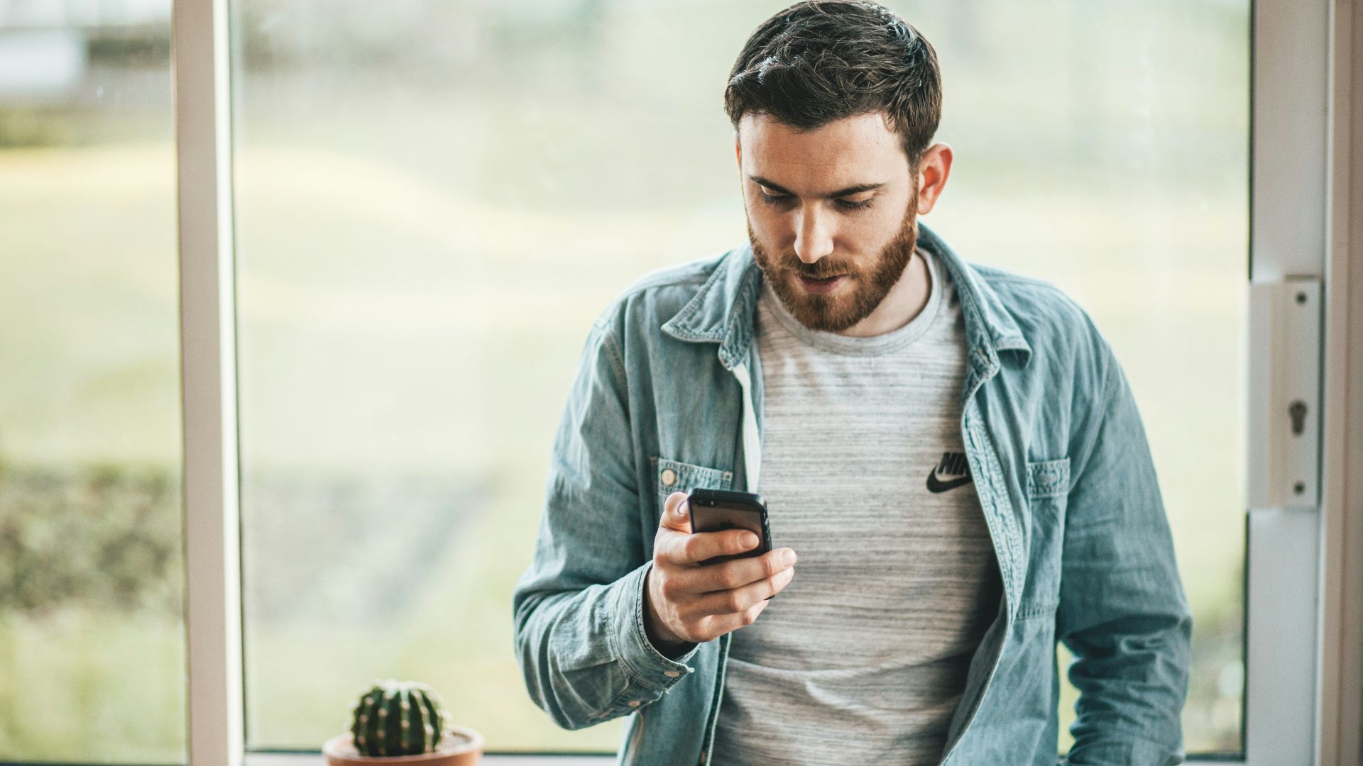 man holding a smartphone near the window