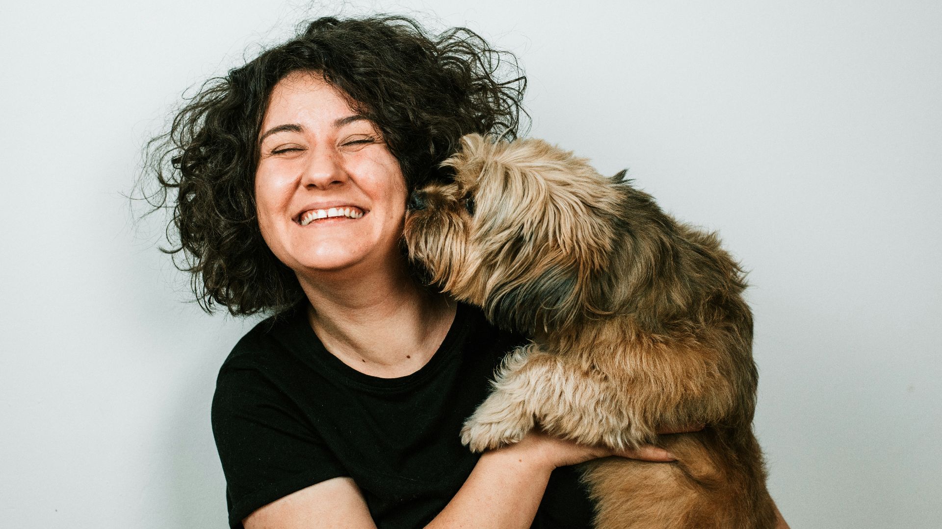 dog kissing woman in black crew-neck shirt