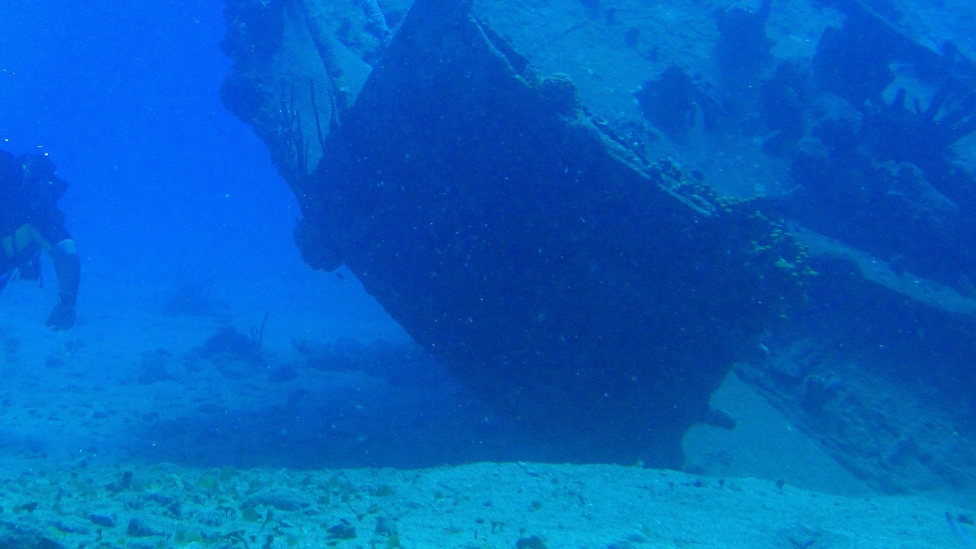 a man scubas next to a large ship in the ocean