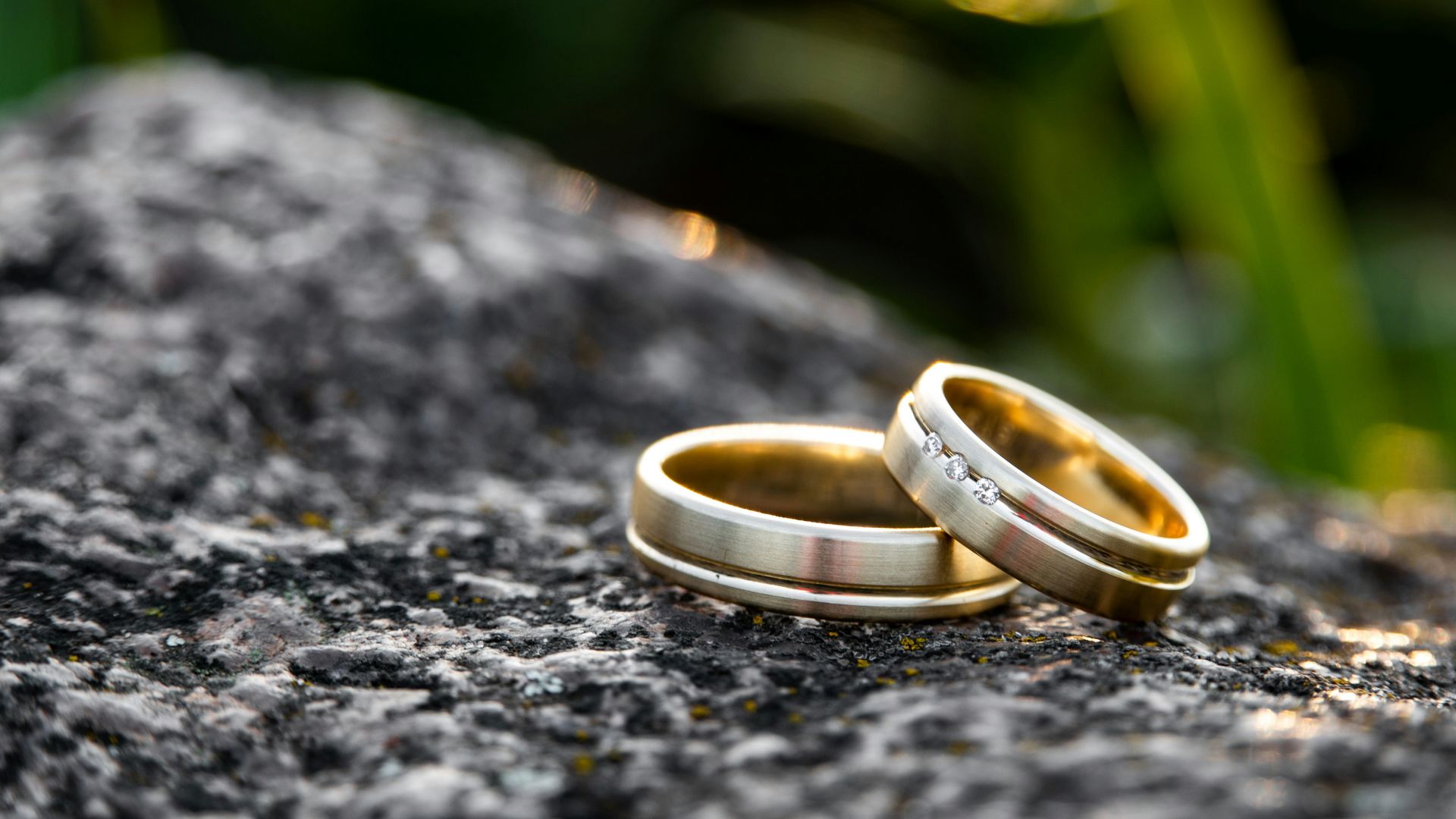 selective focus photography of two gold-colored rings on black stone during daytime