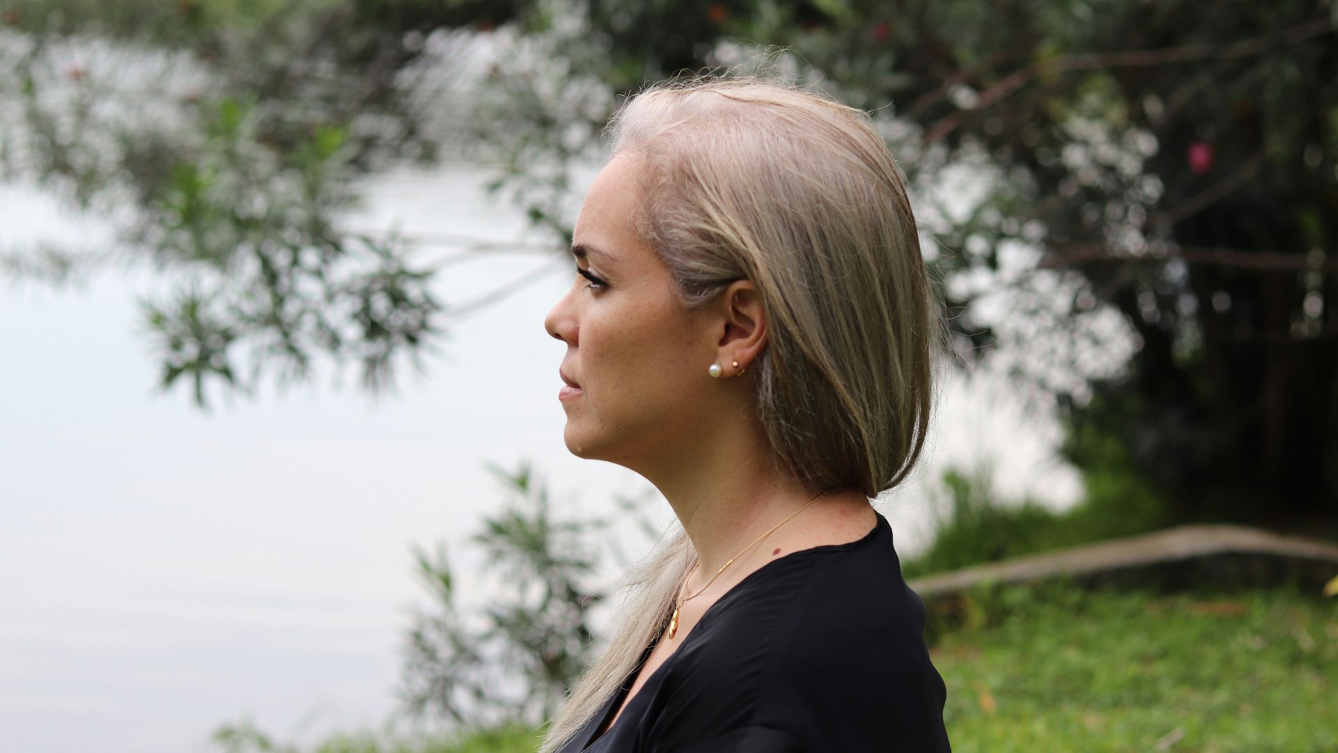 a woman with blonde hair standing in front of a body of water