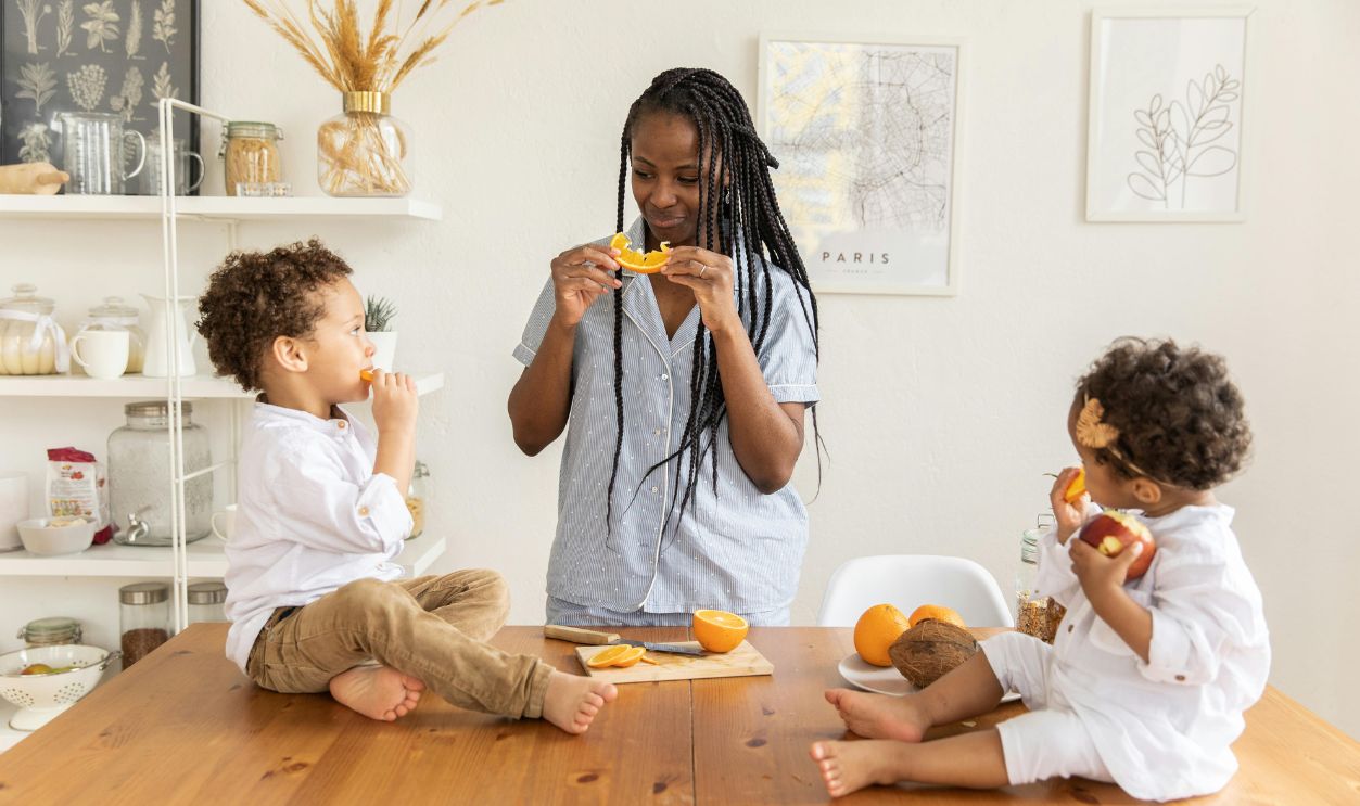 Mother eating oranges with children