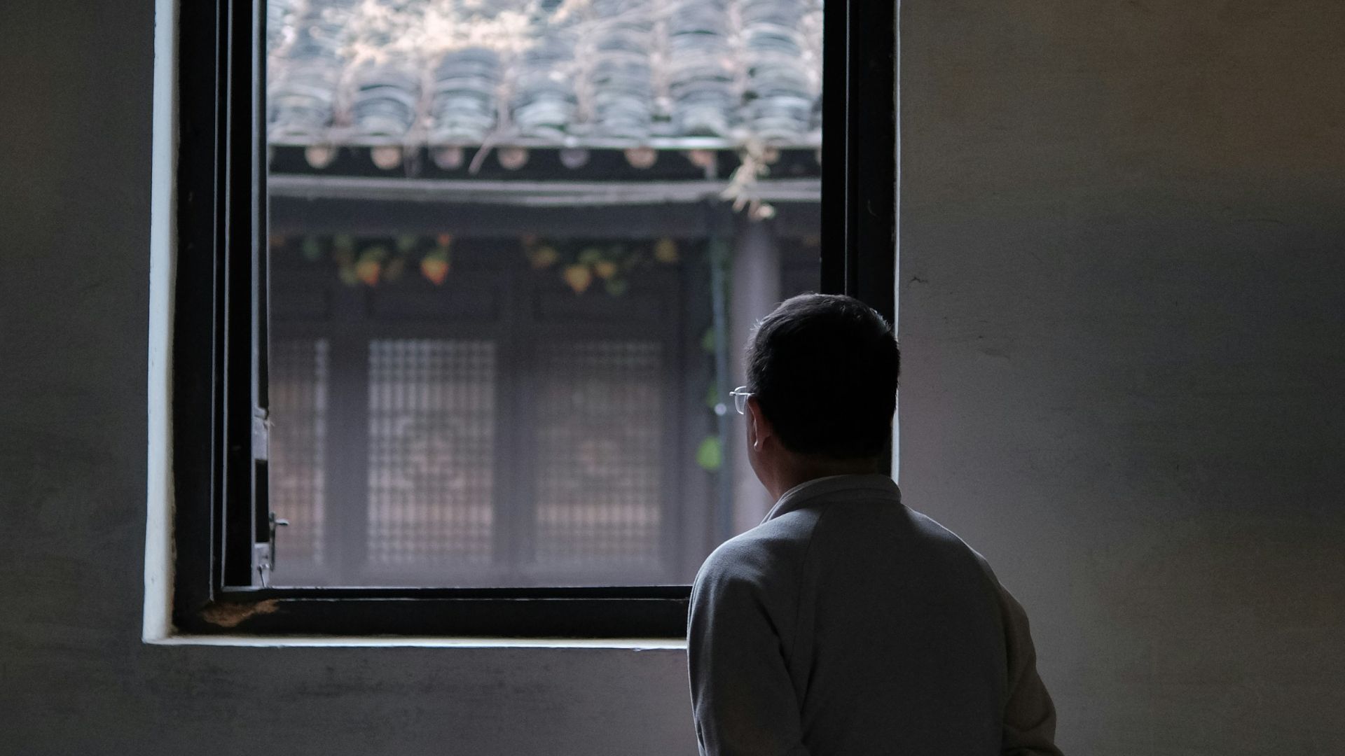 man in gray coat standing near window