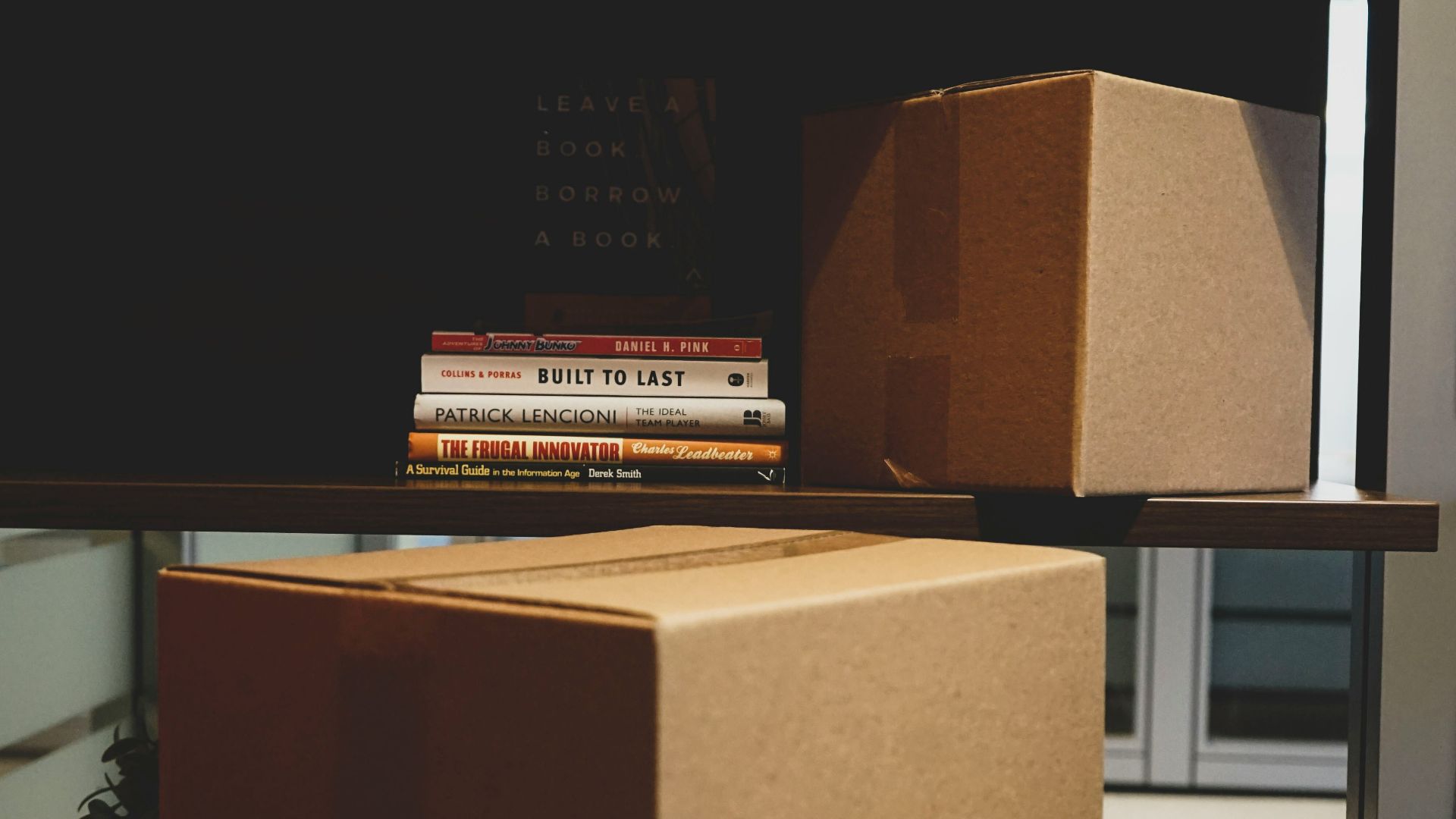 two brown boxes and DVD cases on rack